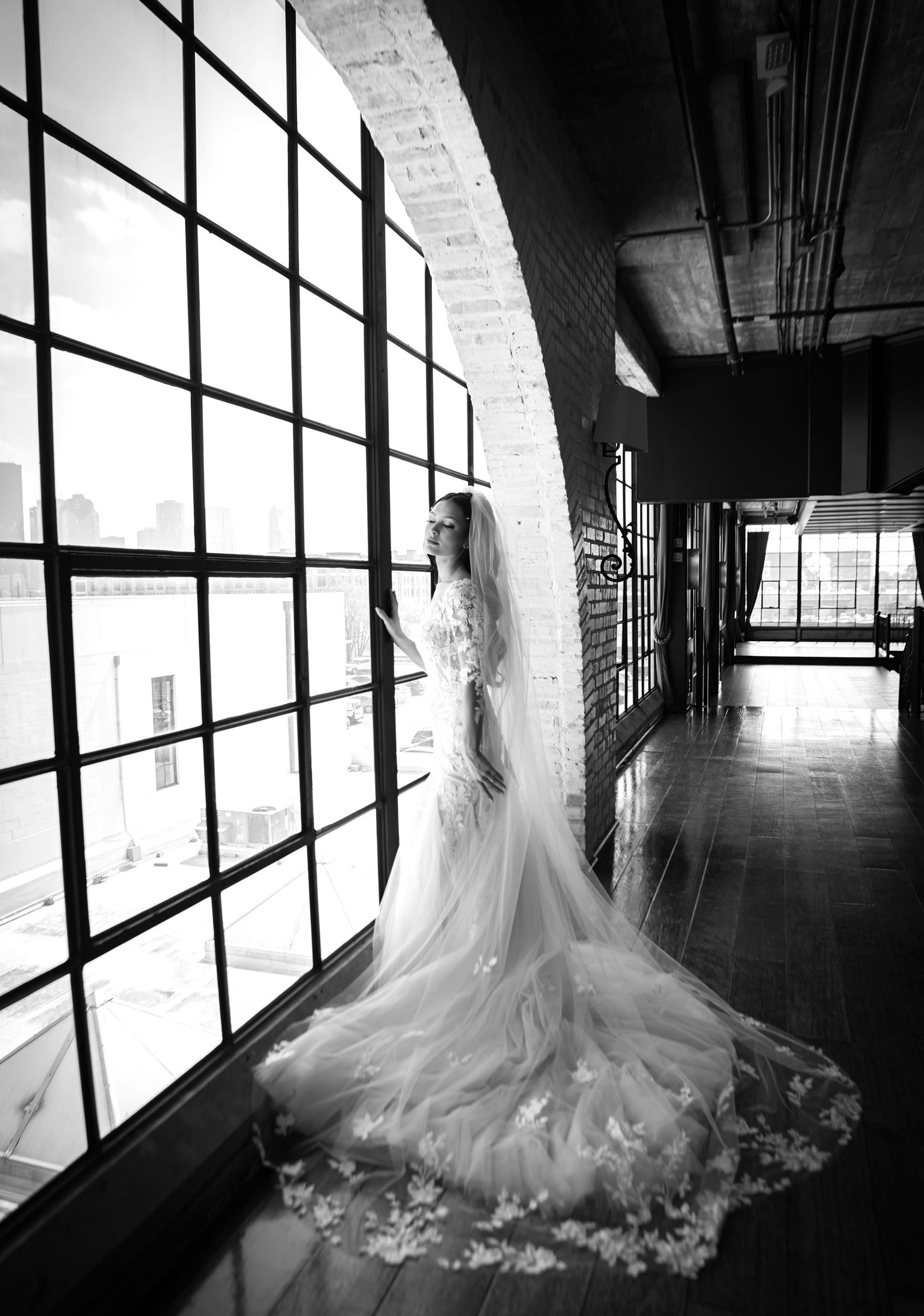 A black and white photo series of a bride in a flowing tulle wedding gown standing in a sunlit hallway corridor.