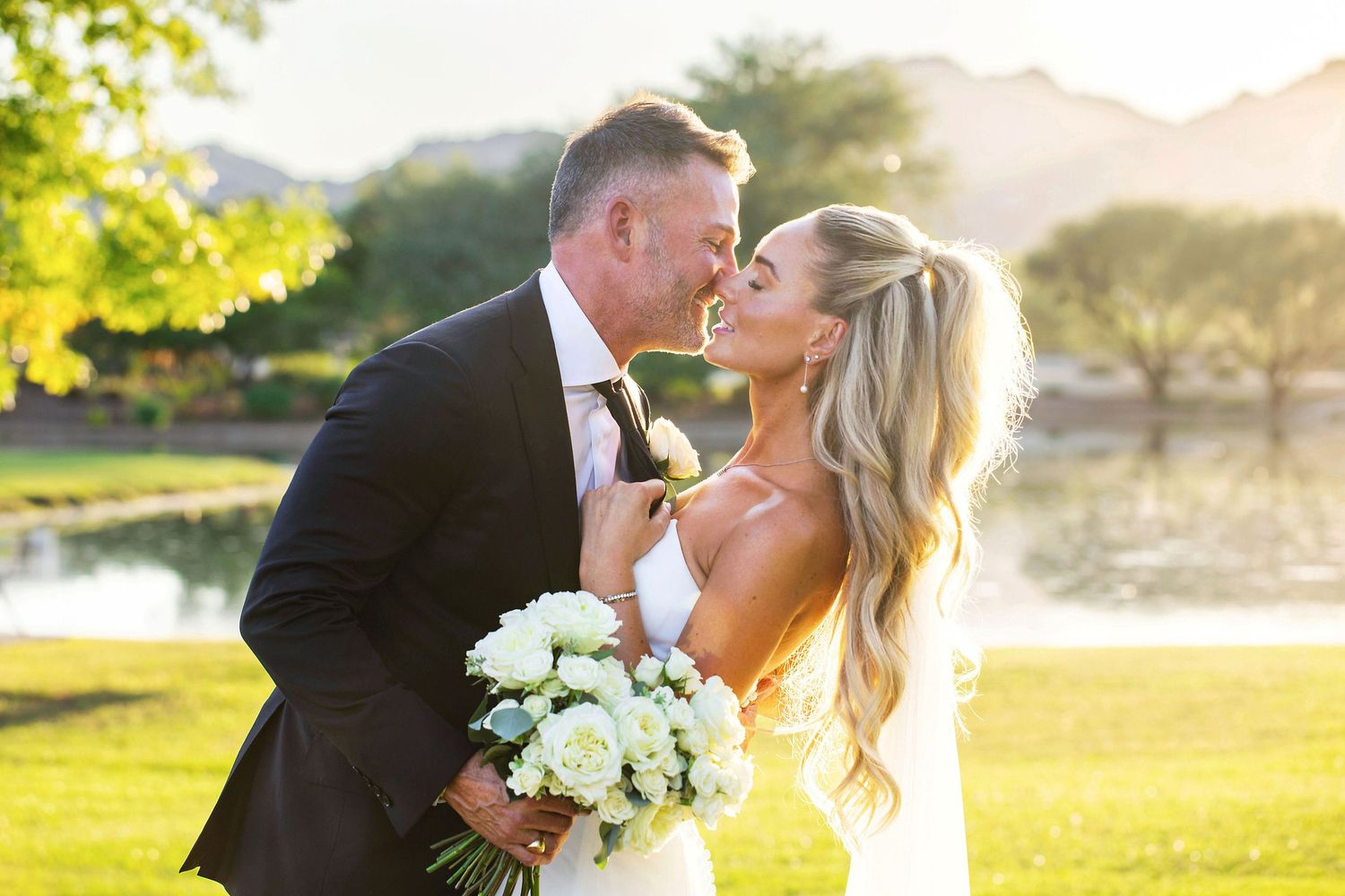 Wedding couple embraces during golden hour photography session with white roses. Romantic, whimsical photos in Scottsdale, Arizona
