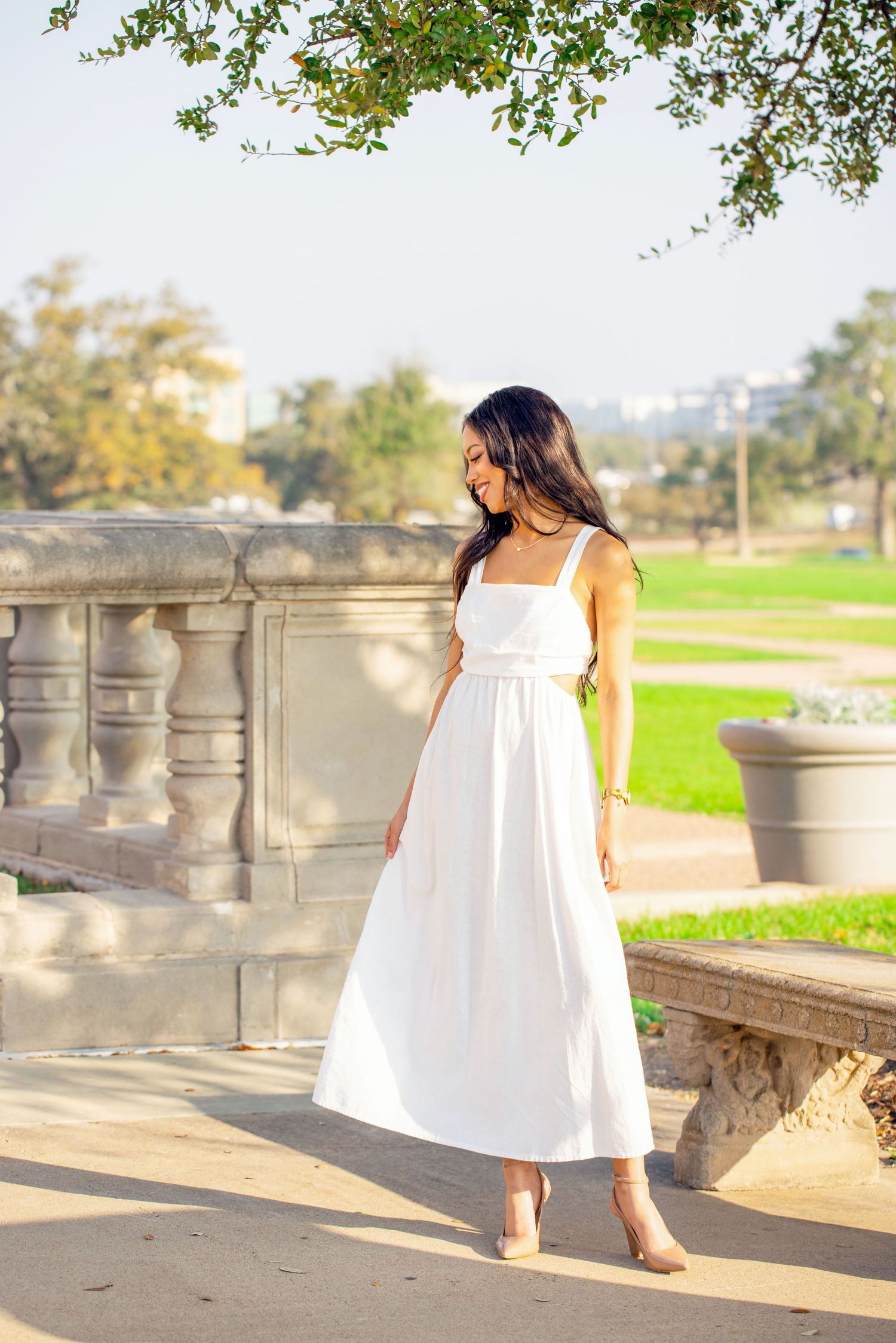 A flowing white sundress contrasts beautifully against stone architecture and green landscape.
