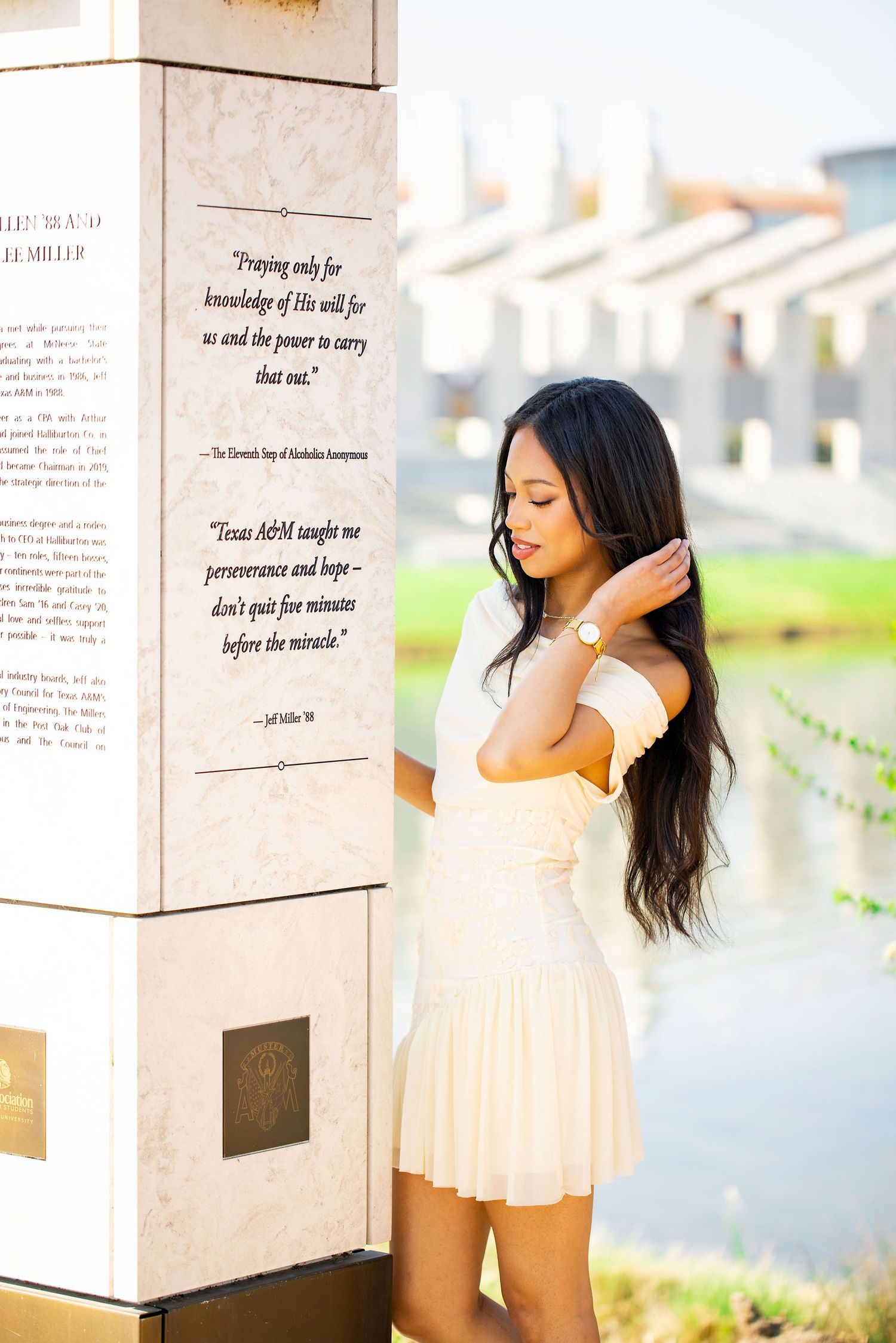 A person in a flowing white dress stands between stone pillars with inspirational quotes etched on them.