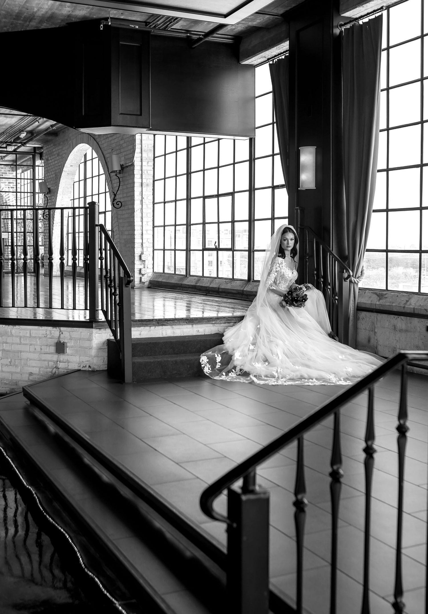 A black and white panoramic sequence showing an elegant wedding dress in an industrial loft space with large windows.