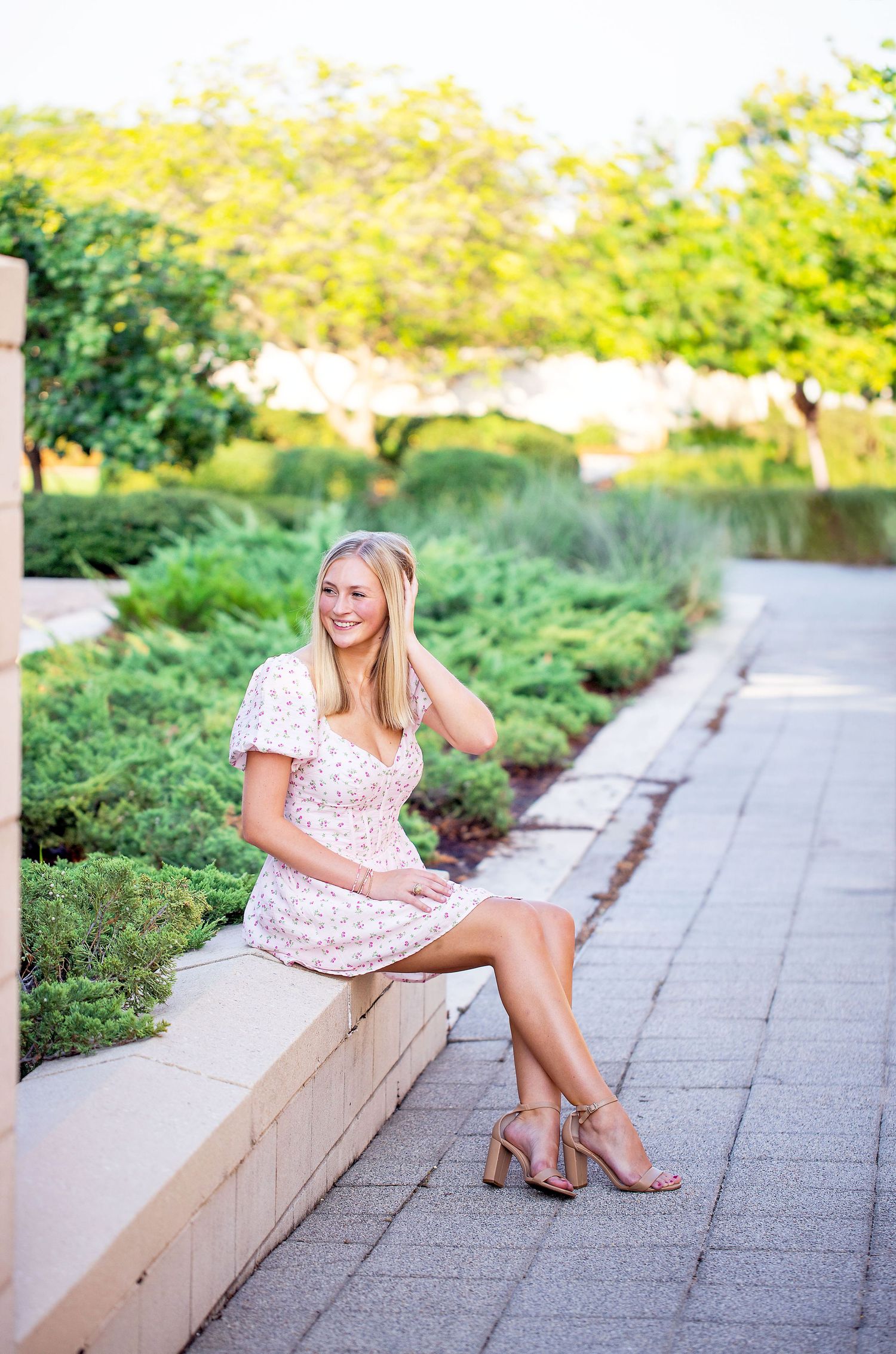 Texas A&M University graduate summer portrait session at George Bush Library with floral dress and natural garden backdrop.