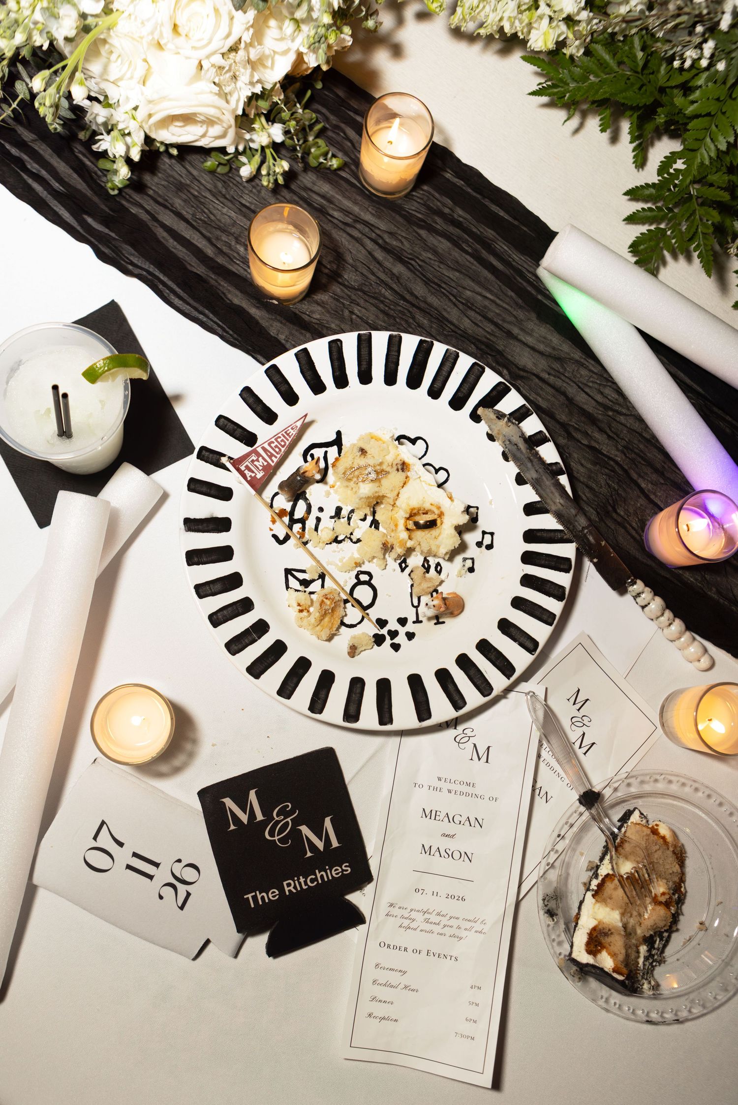 Elegant wedding table with M&M monogram programs, candles, cookies on striped plate, and floral decor.