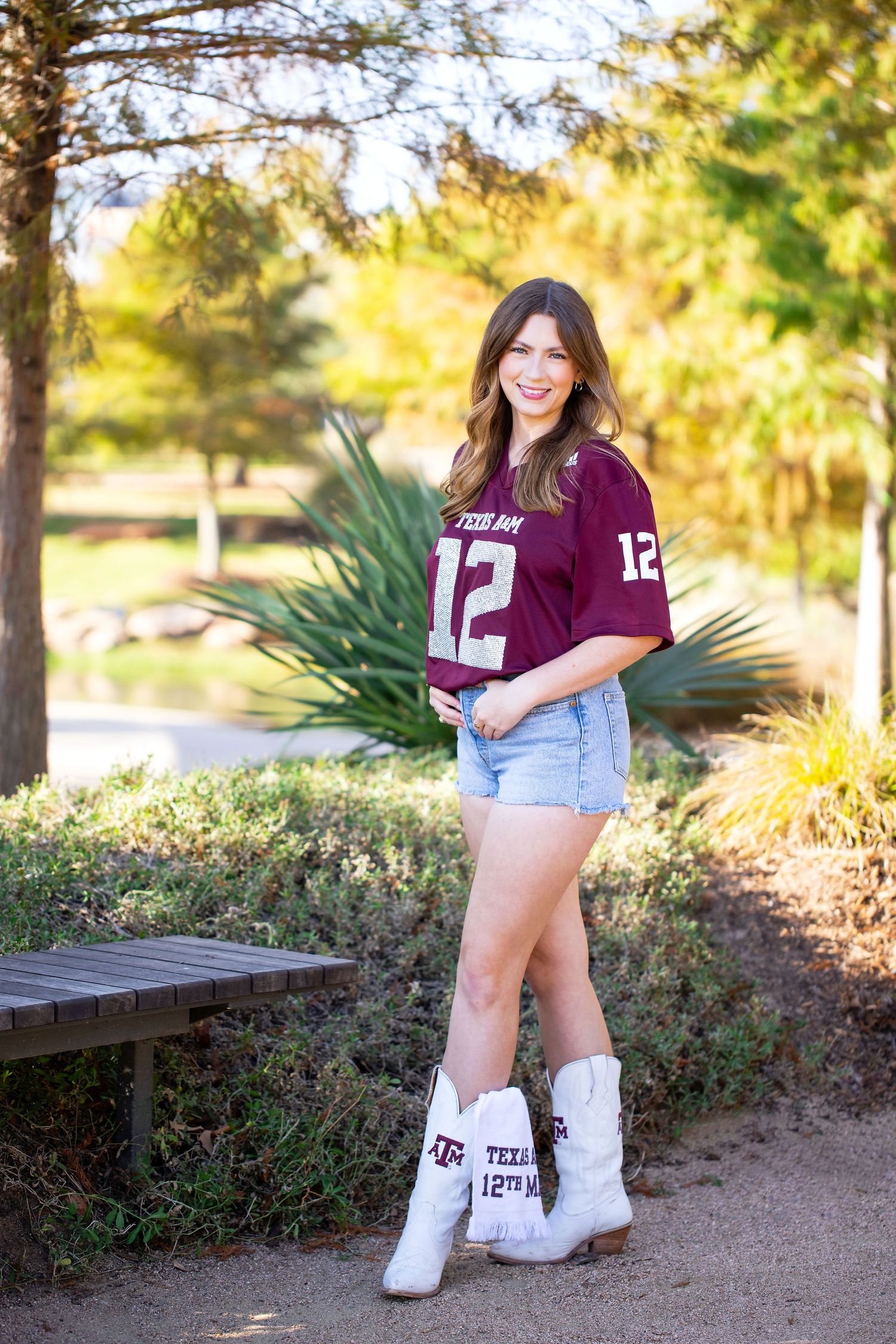 Texas A&M University graduate wearing maroon jersey number 12 poses in Aggie Park.