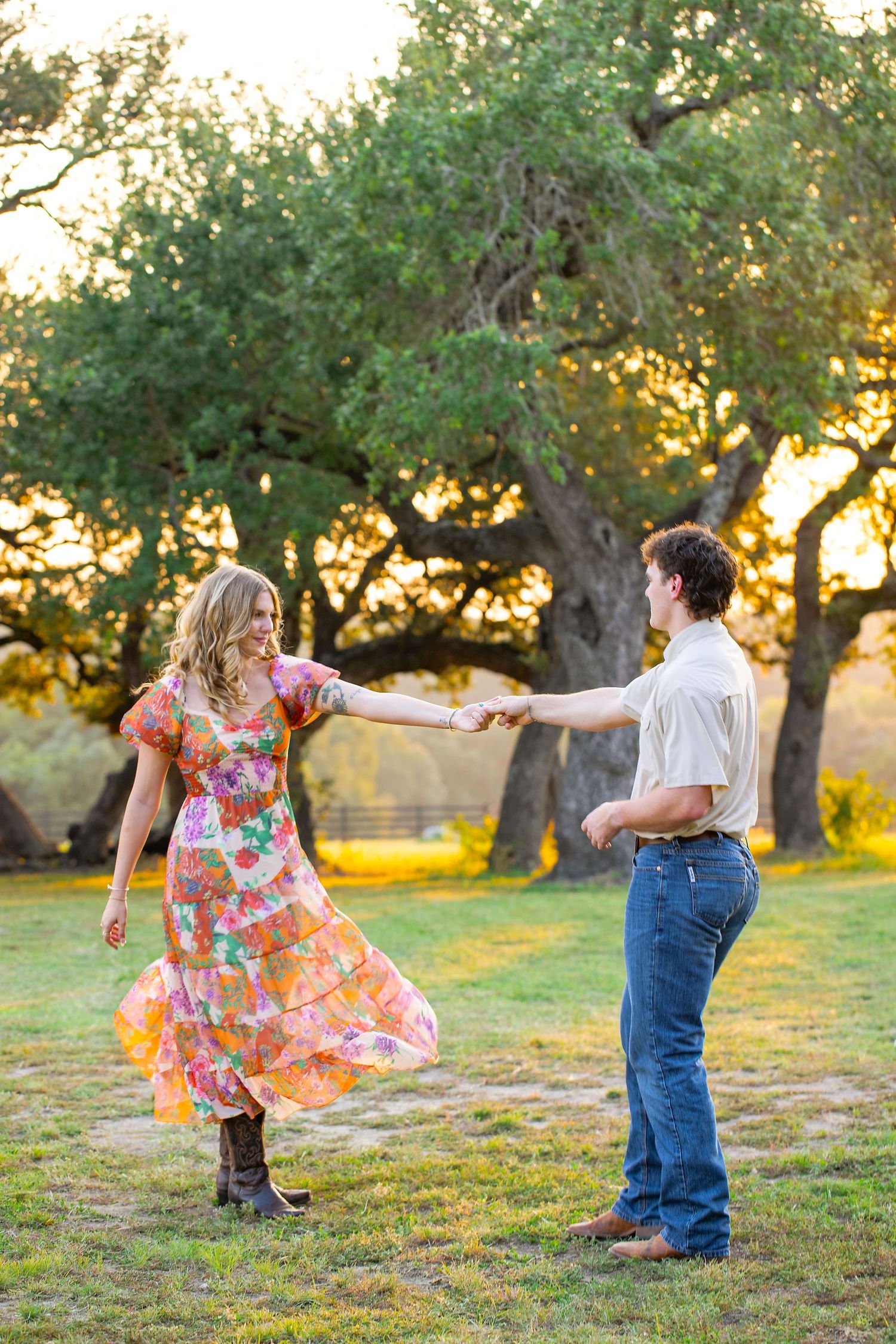 A couple dances together in an olive grove at sunset, her floral dress twirling as they move across the grass.