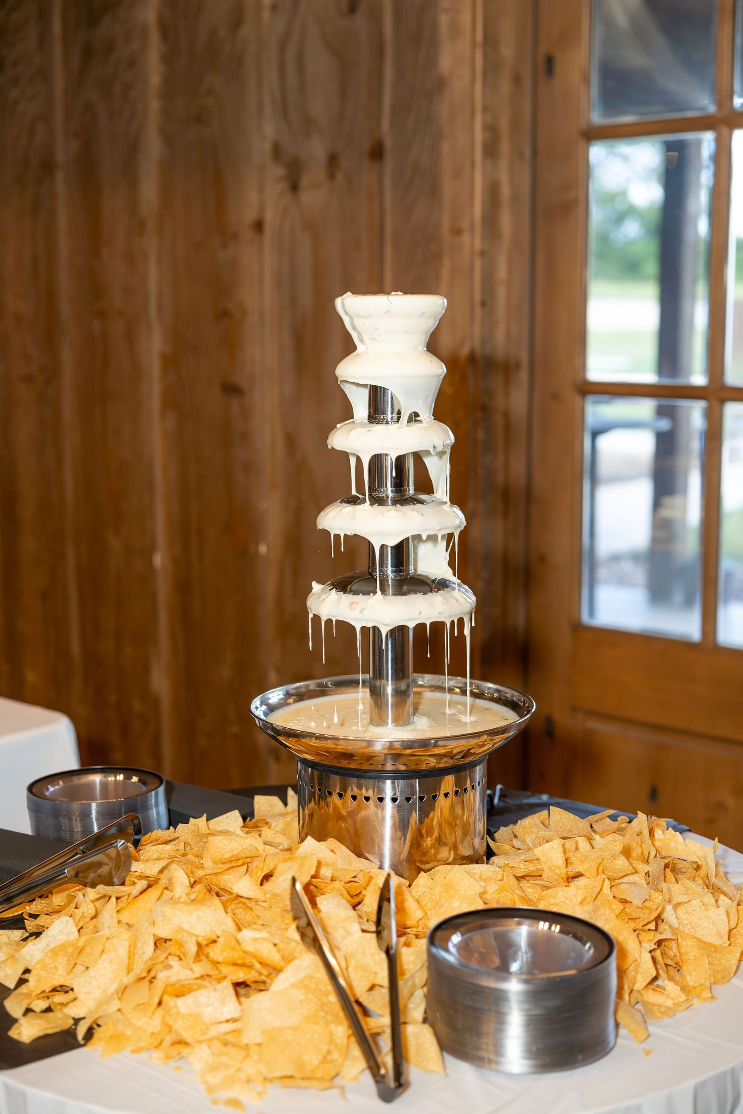 White chocolate fountain surrounded by tortilla chips at a rustic barn wedding reception.