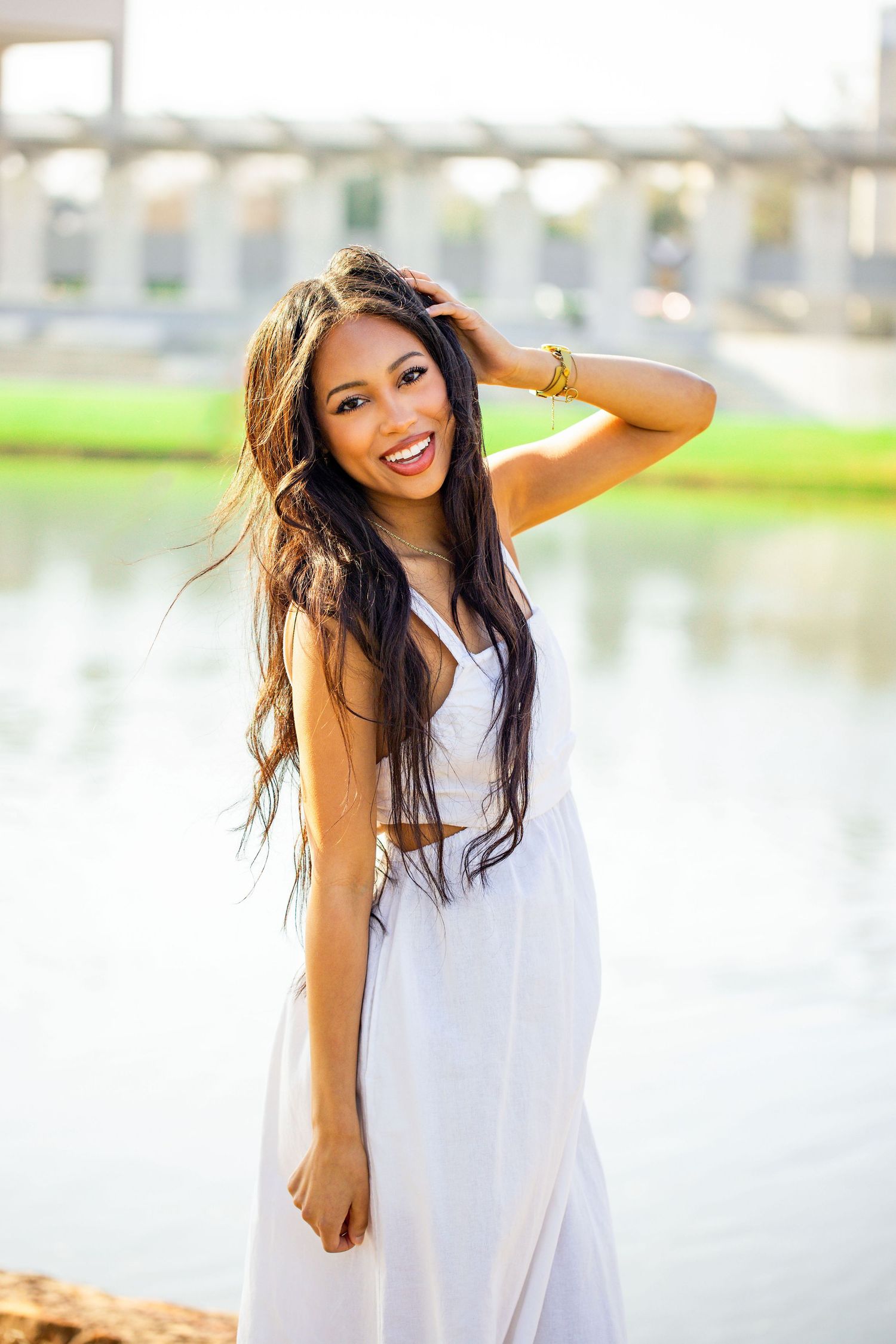 Candid waterfront portraits showcase white sundress and natural expressions.