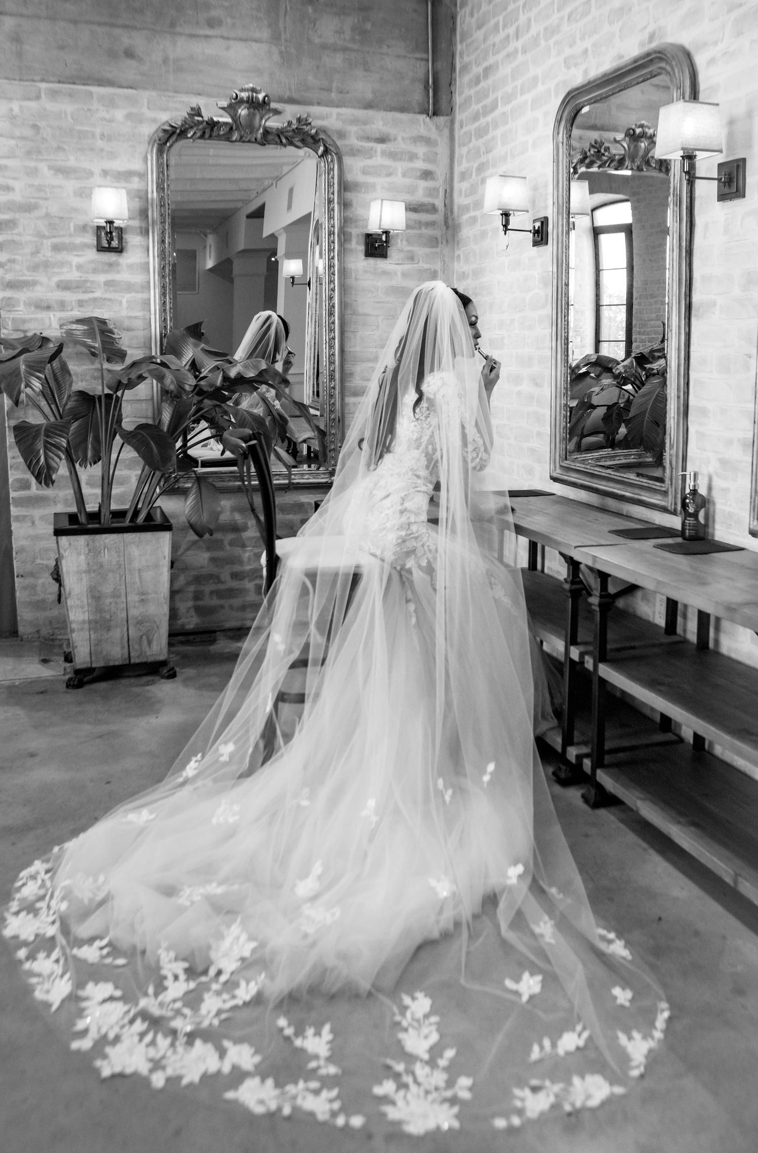 A series of five black and white photos showing a wedding dress with a long flowing veil in a dressing room with mirrors.