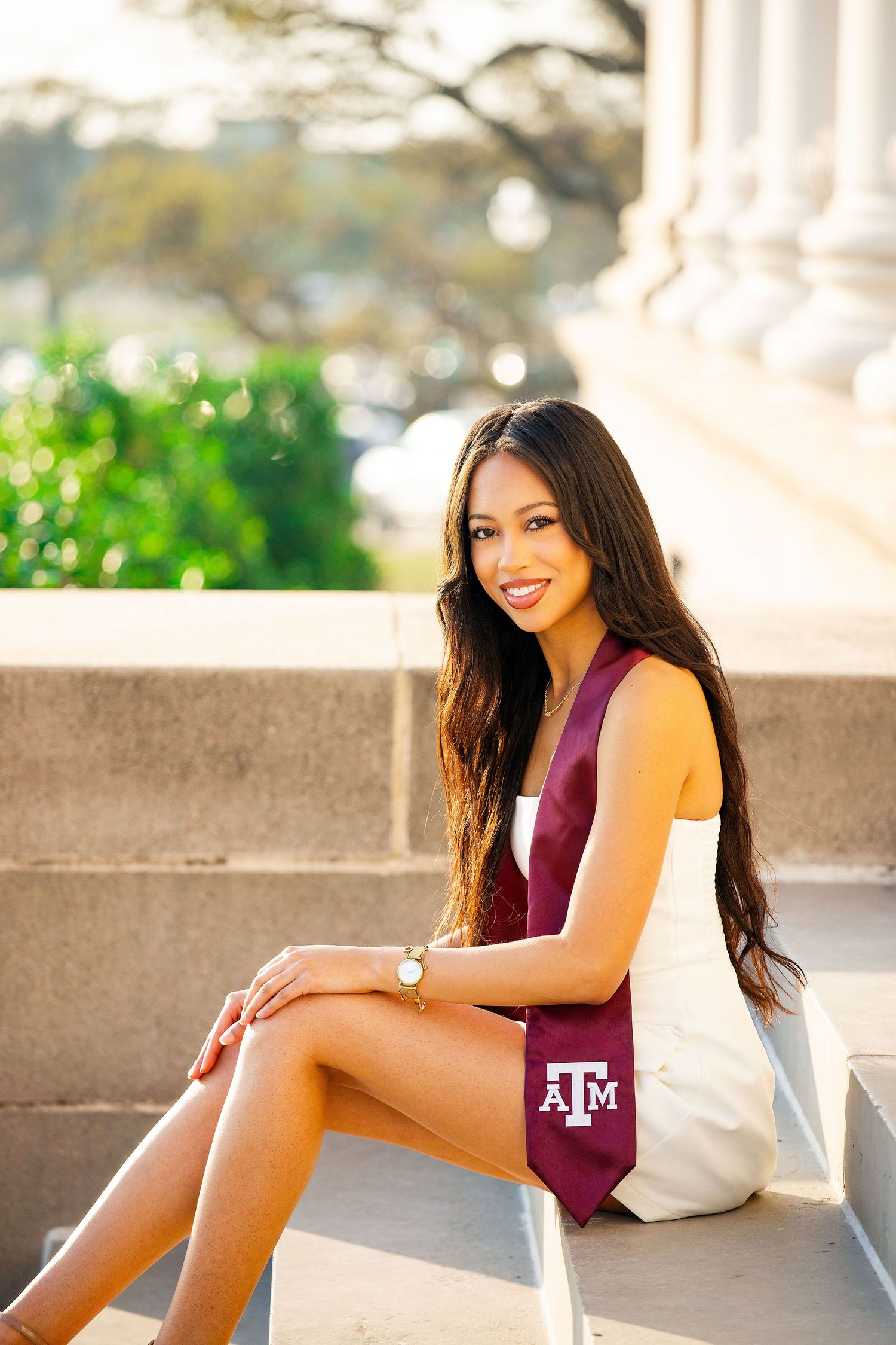 A stylish maroon and white outfit is showcased against a sunlit architectural backdrop.