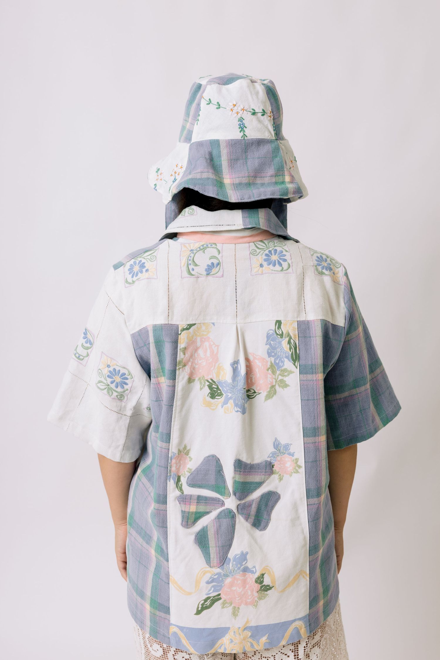 Back view of a person wearing a pastel floral print shirt and matching bucket hat against a white background.