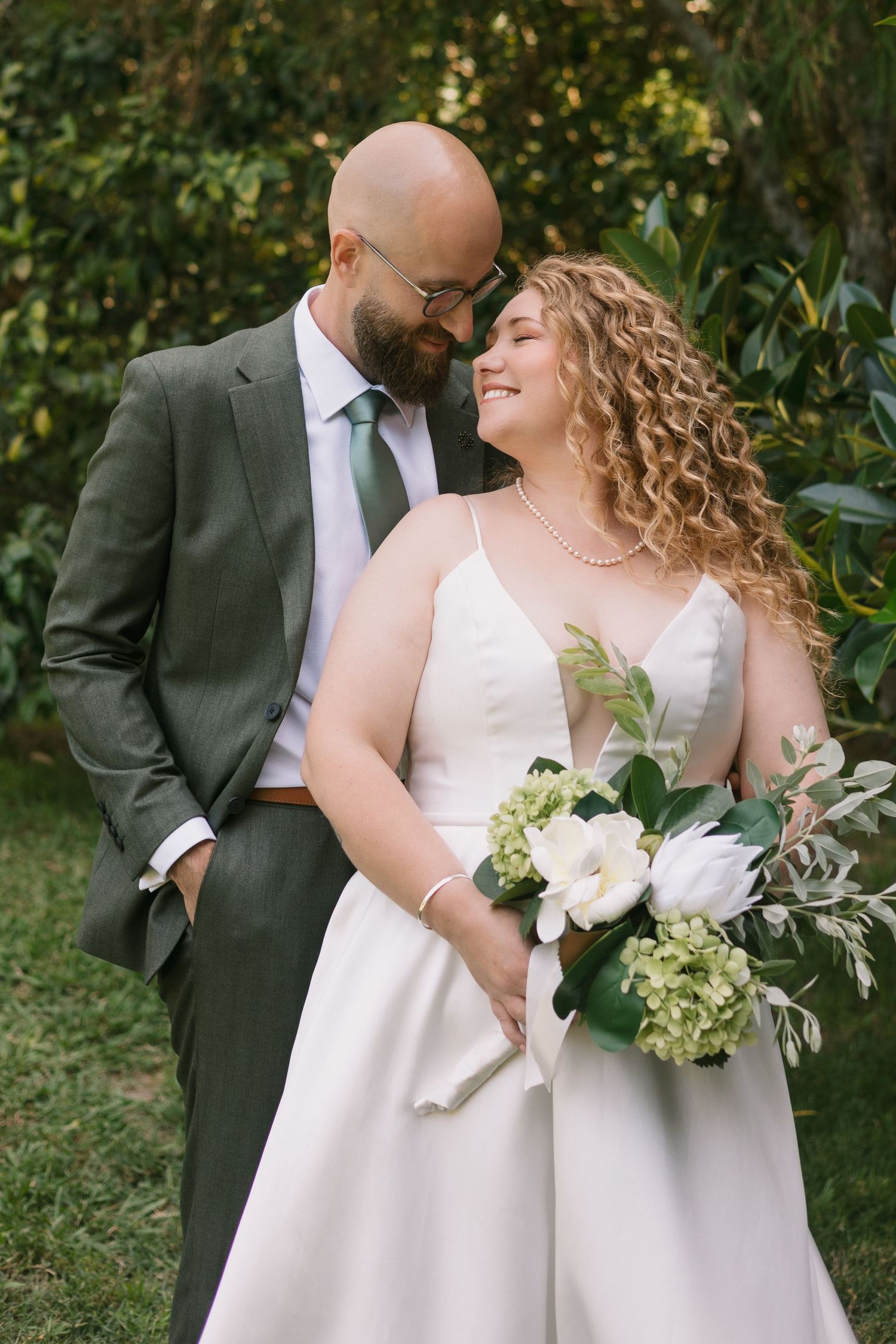 A romantic wedding photo outdoors featuring a beautiful bridal bouquet with white flowers and greenery.
