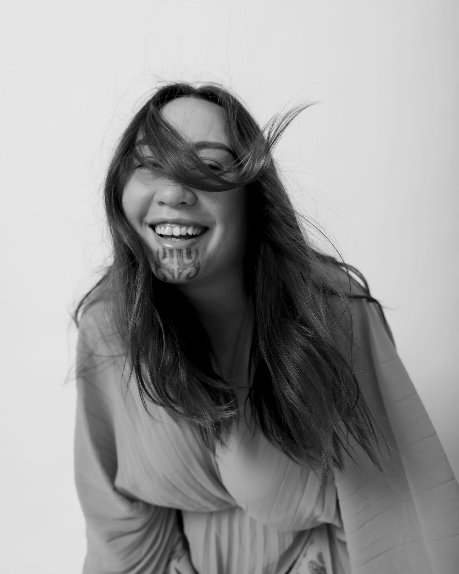 Black and white portrait series showing windswept hair movement and joyful expressions against a plain background.