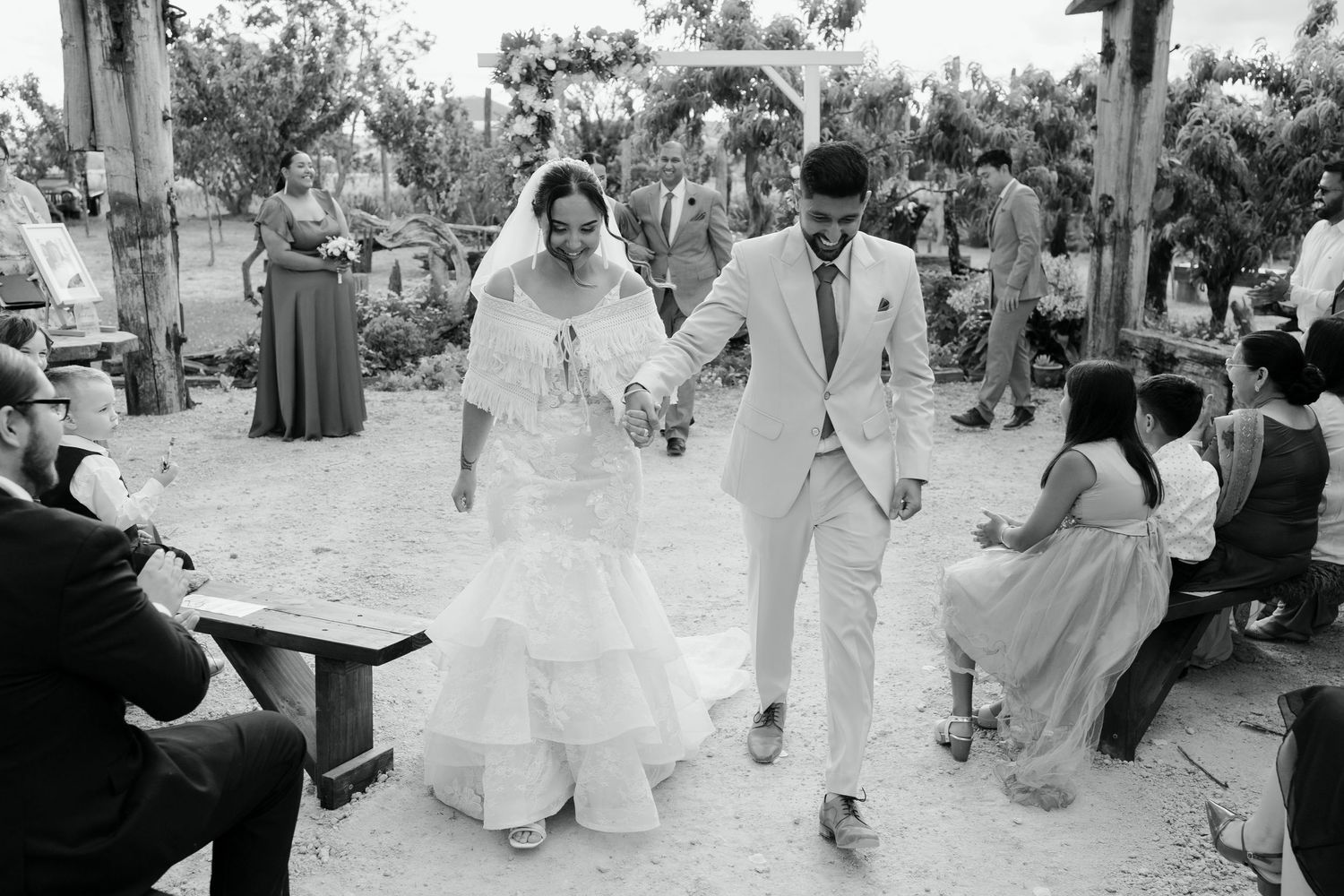 Wedding guests dance and celebrate during an outdoor reception in black and white photography.