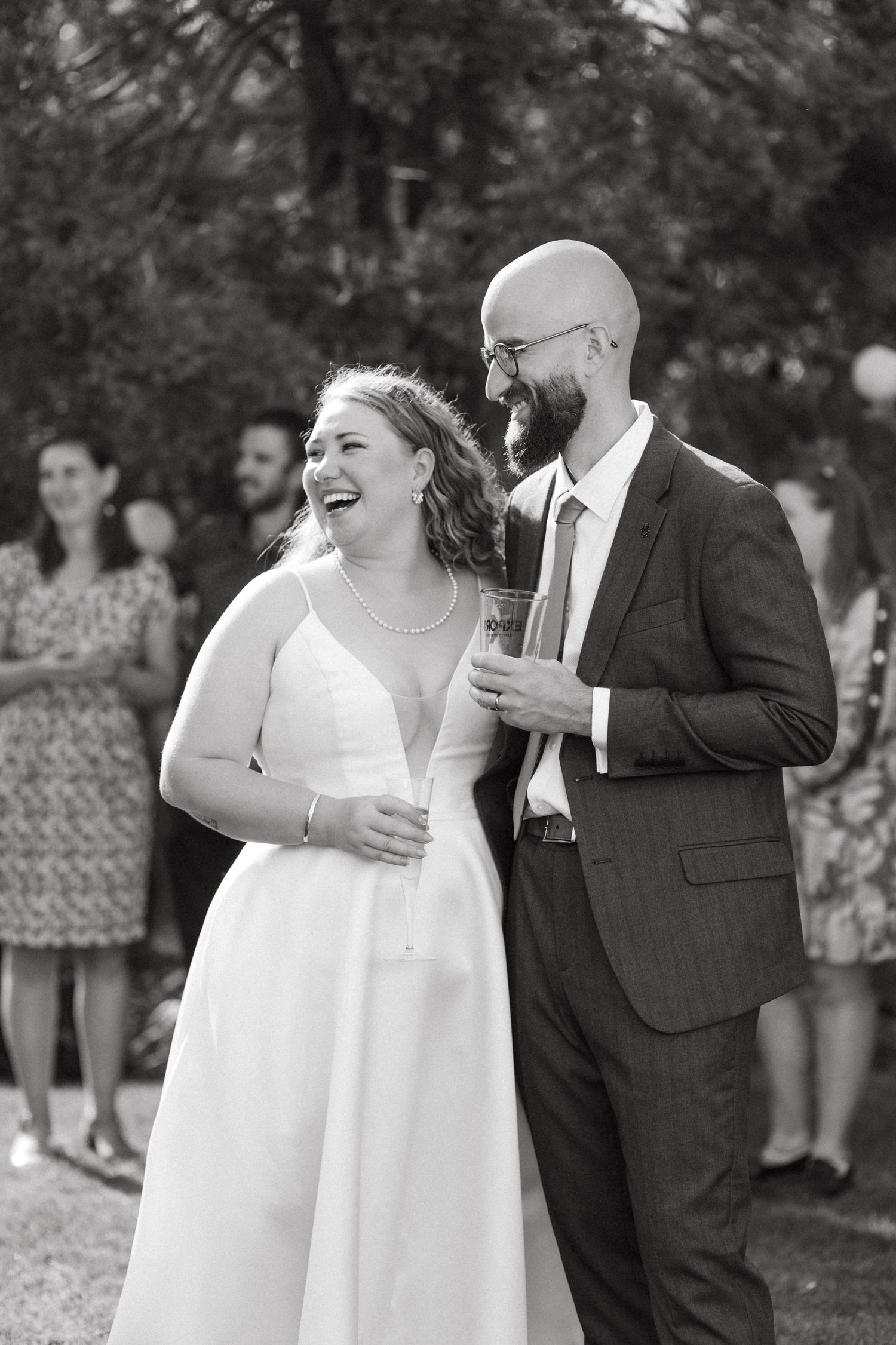 A joyful moment captured in black and white during an outdoor wedding celebration.