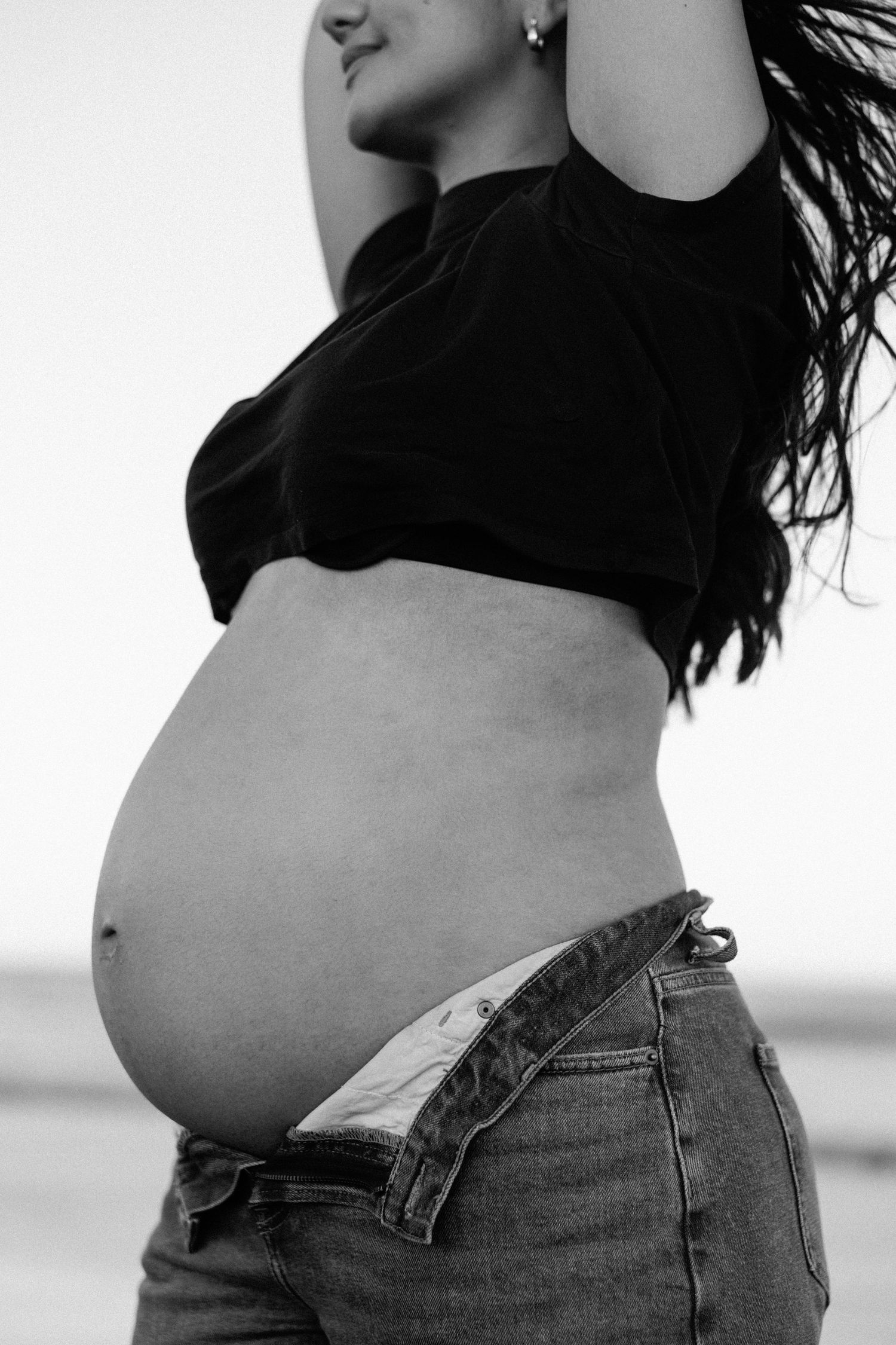 A black and white photo series showing a pregnant belly's progression through different stages of pregnancy.
