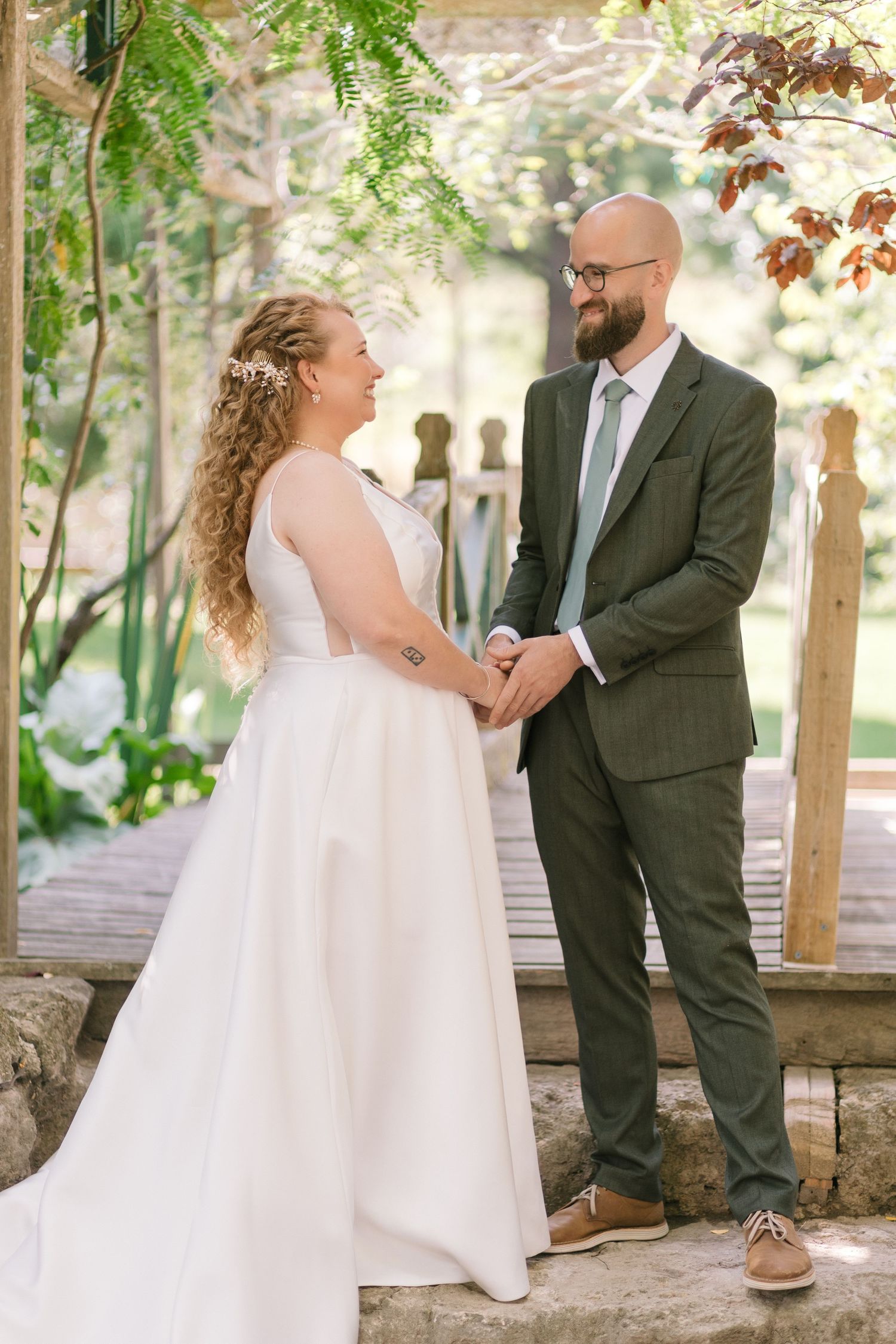 Four artistic photos of a bride in a flowing white dress posing with her partner in a garden gazebo setting.