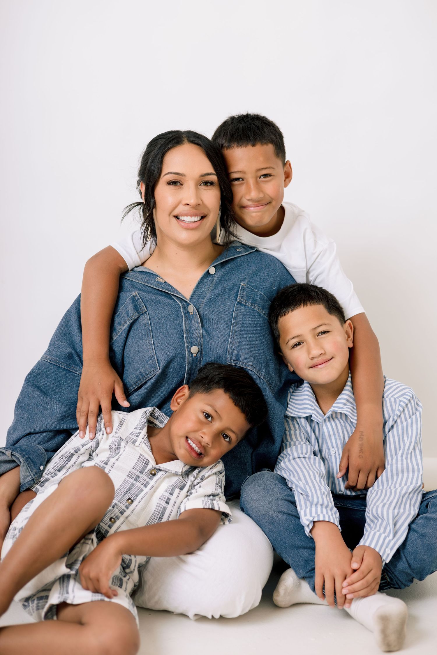 Family members wearing coordinated denim and white outfits pose together in a series of casual studio portraits.