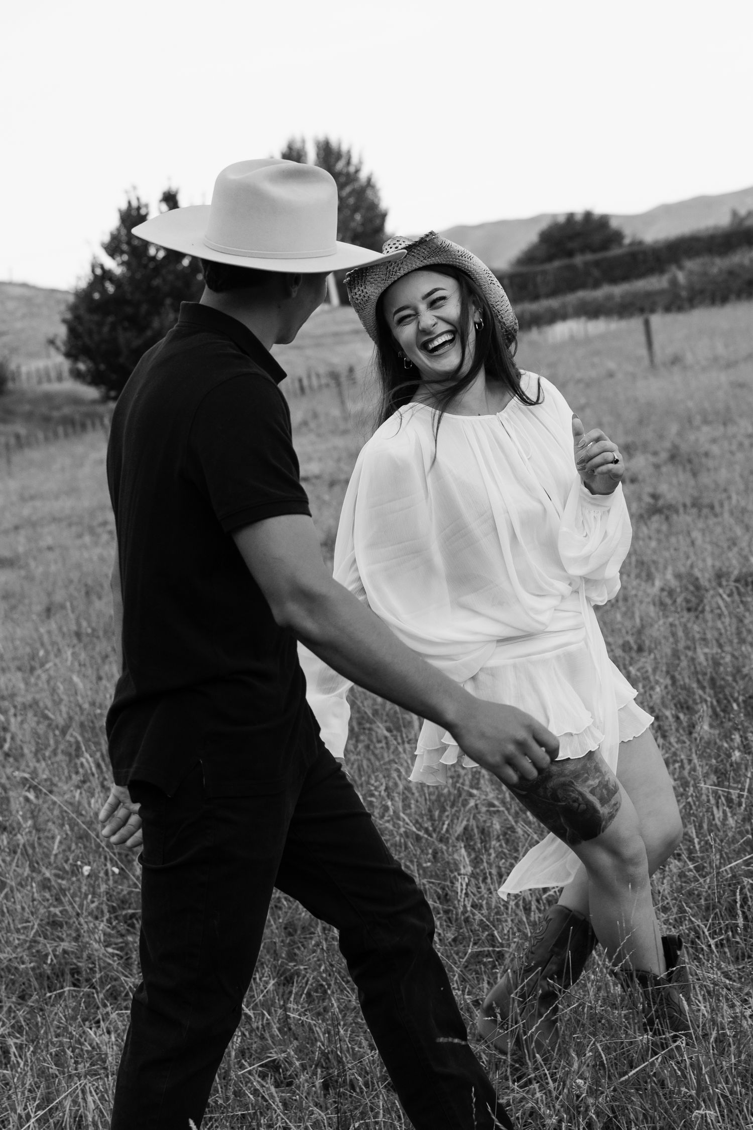 A playful couple in black and white enjoying a moment together in a grassy field.
