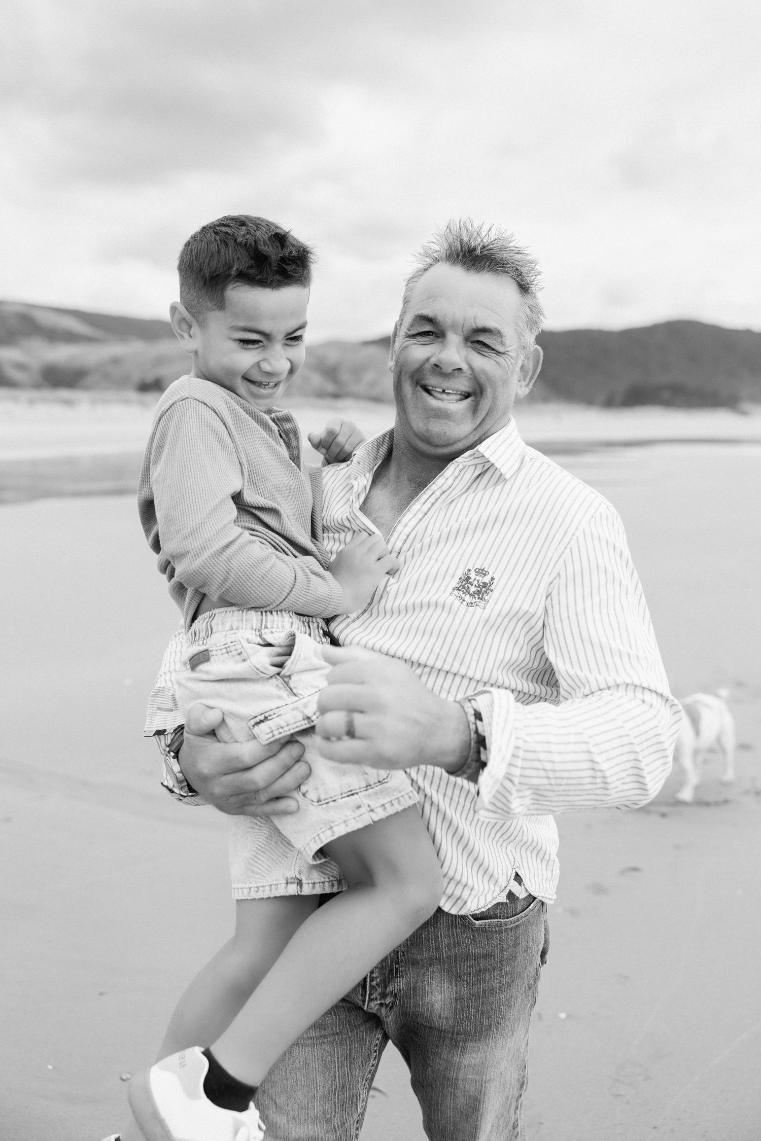 A heartwarming black and white photo series showing playful moments between a parent and child at the beach.