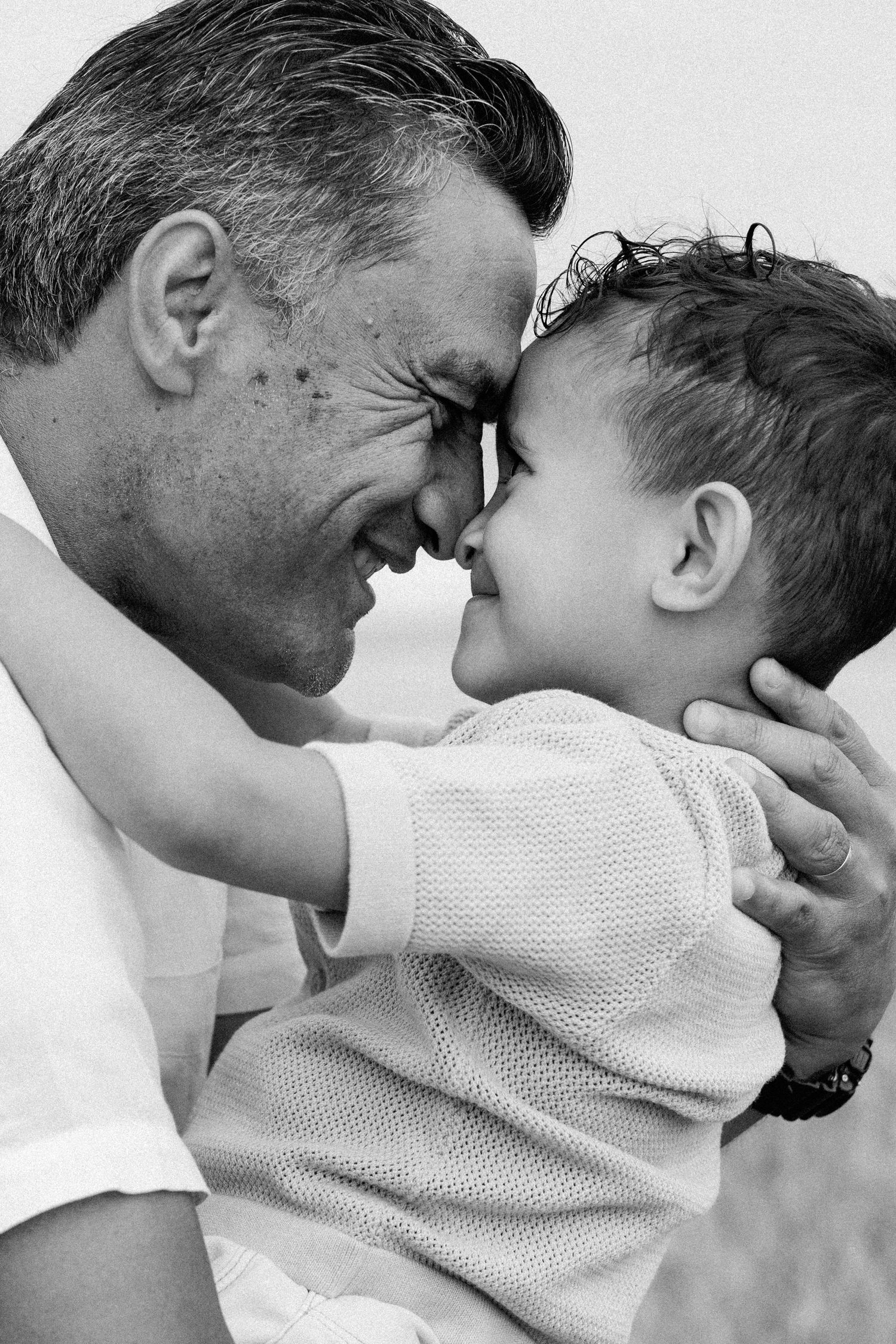 Black and white series of intimate moments showing tender interaction between parent and child in white clothing.