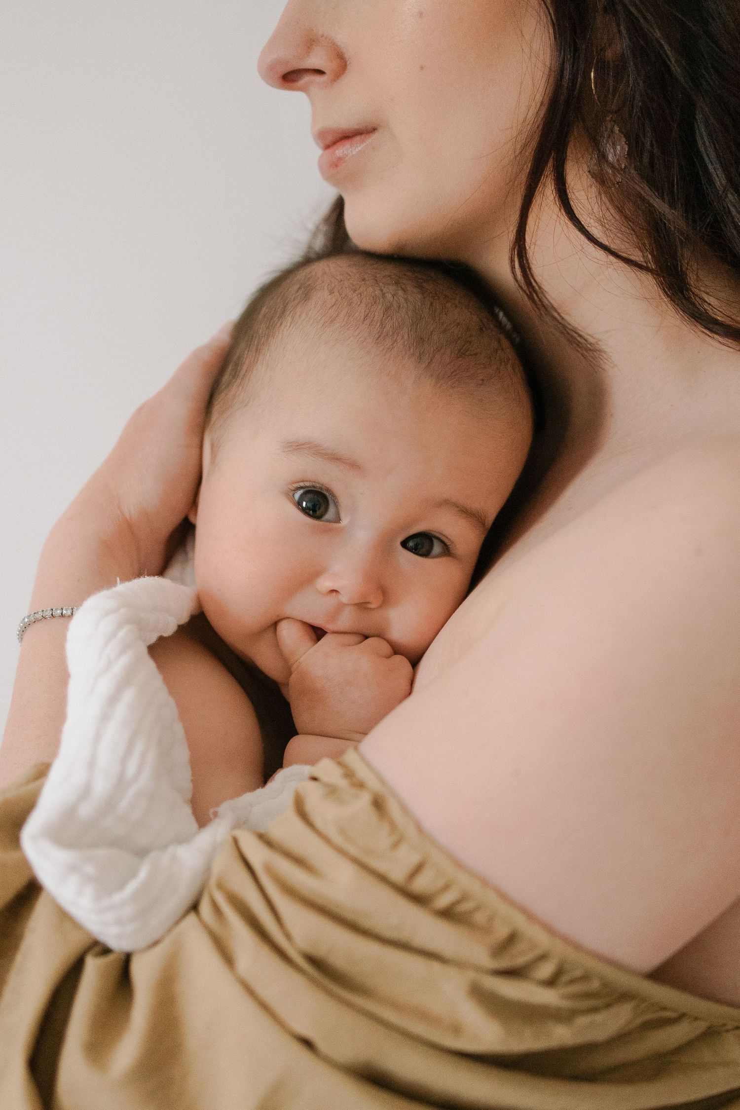 Close-up sequence of a baby breastfeeding in a beige wrap, showing tender nursing moments.