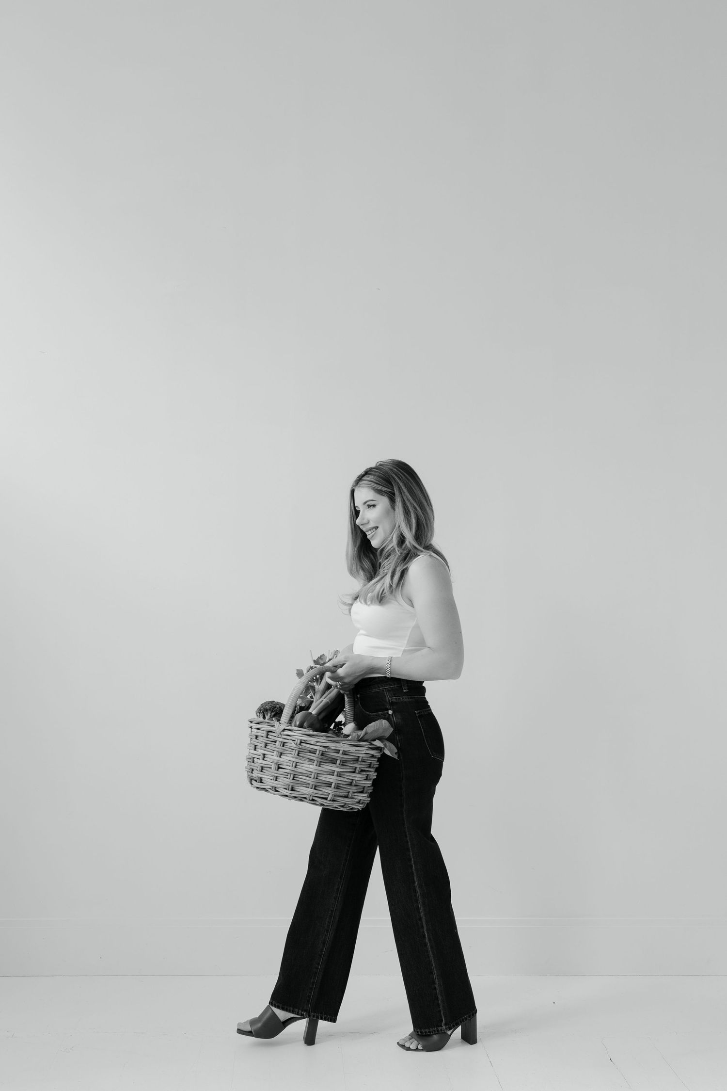A series of black and white photos showing a person in white top and dark pants holding a woven basket against a plain backdrop.