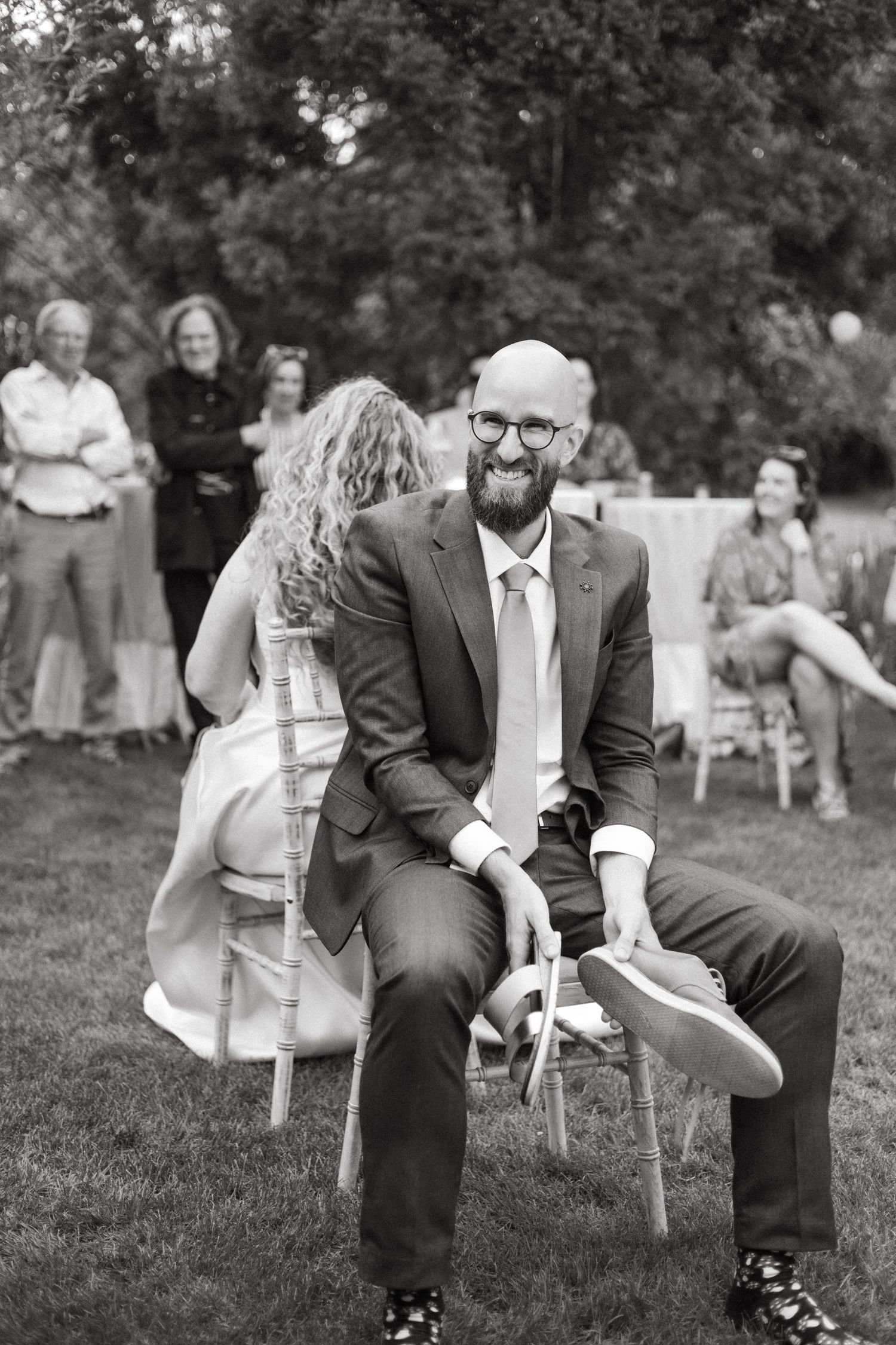 Black and white photo of wedding couple playing lawn games at outdoor reception.
