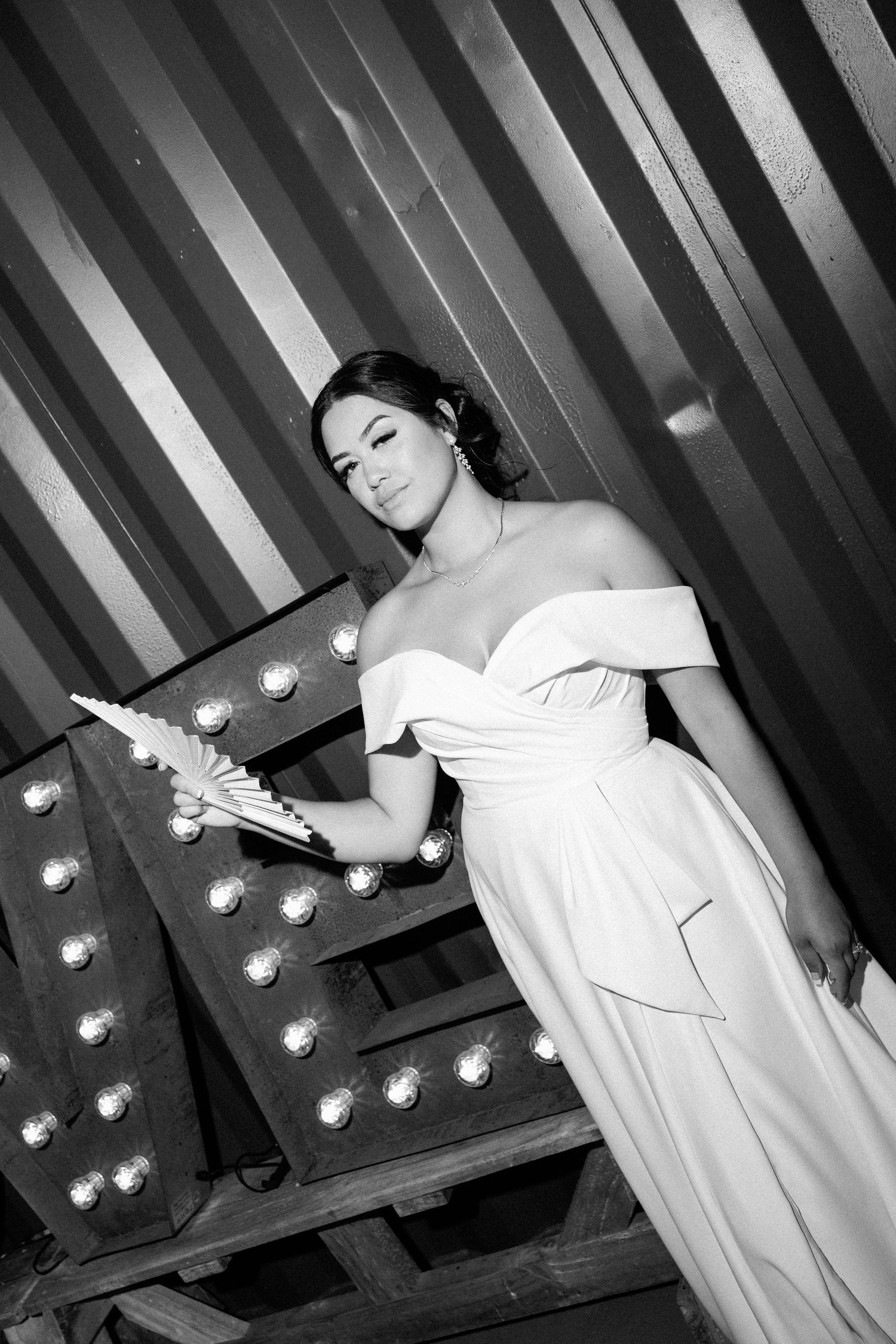 A black and white photo series showing a figure in white clothing posing dramatically against a striped background with lights.
