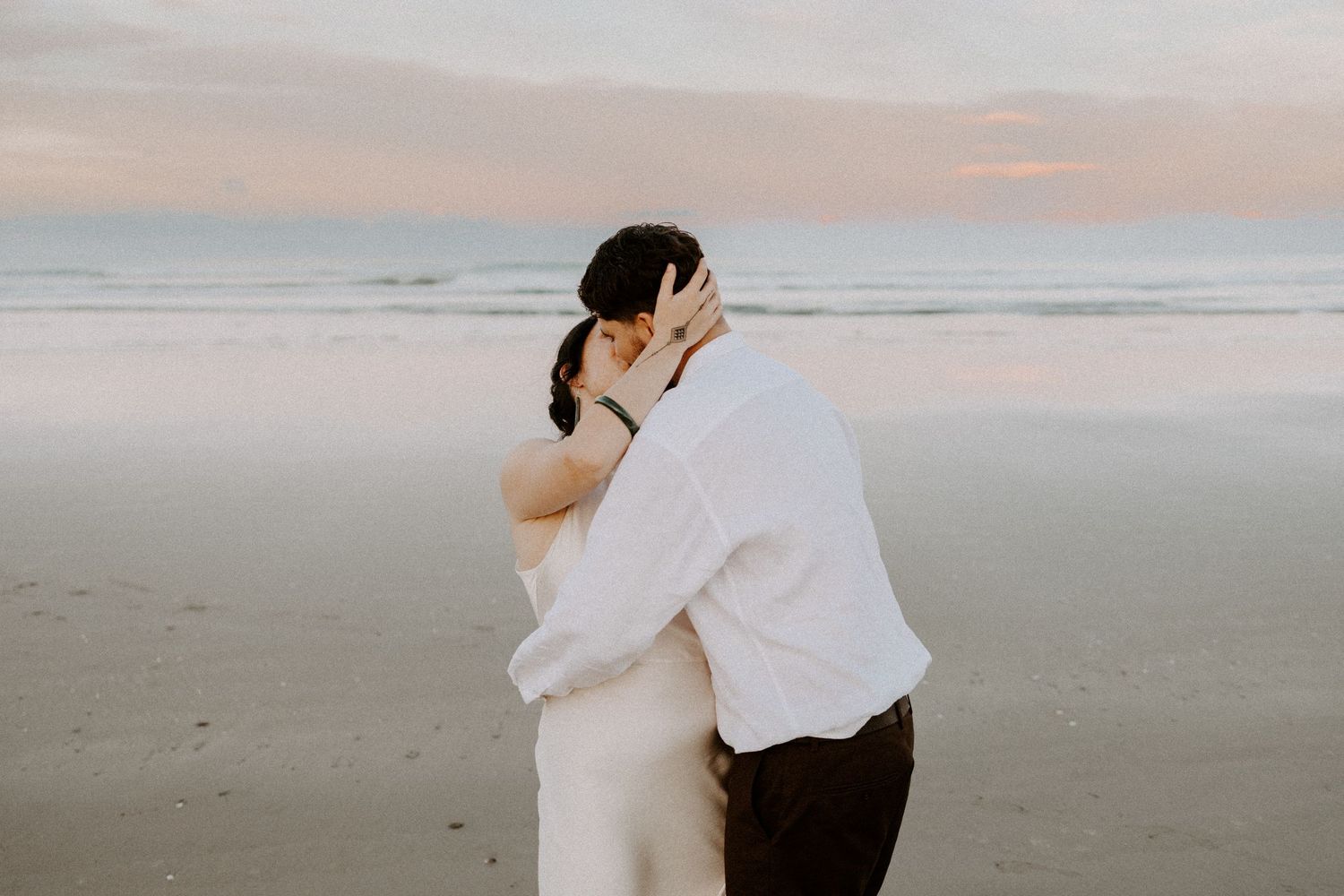 Tender moment between couple during a sunset beach photoshoot.