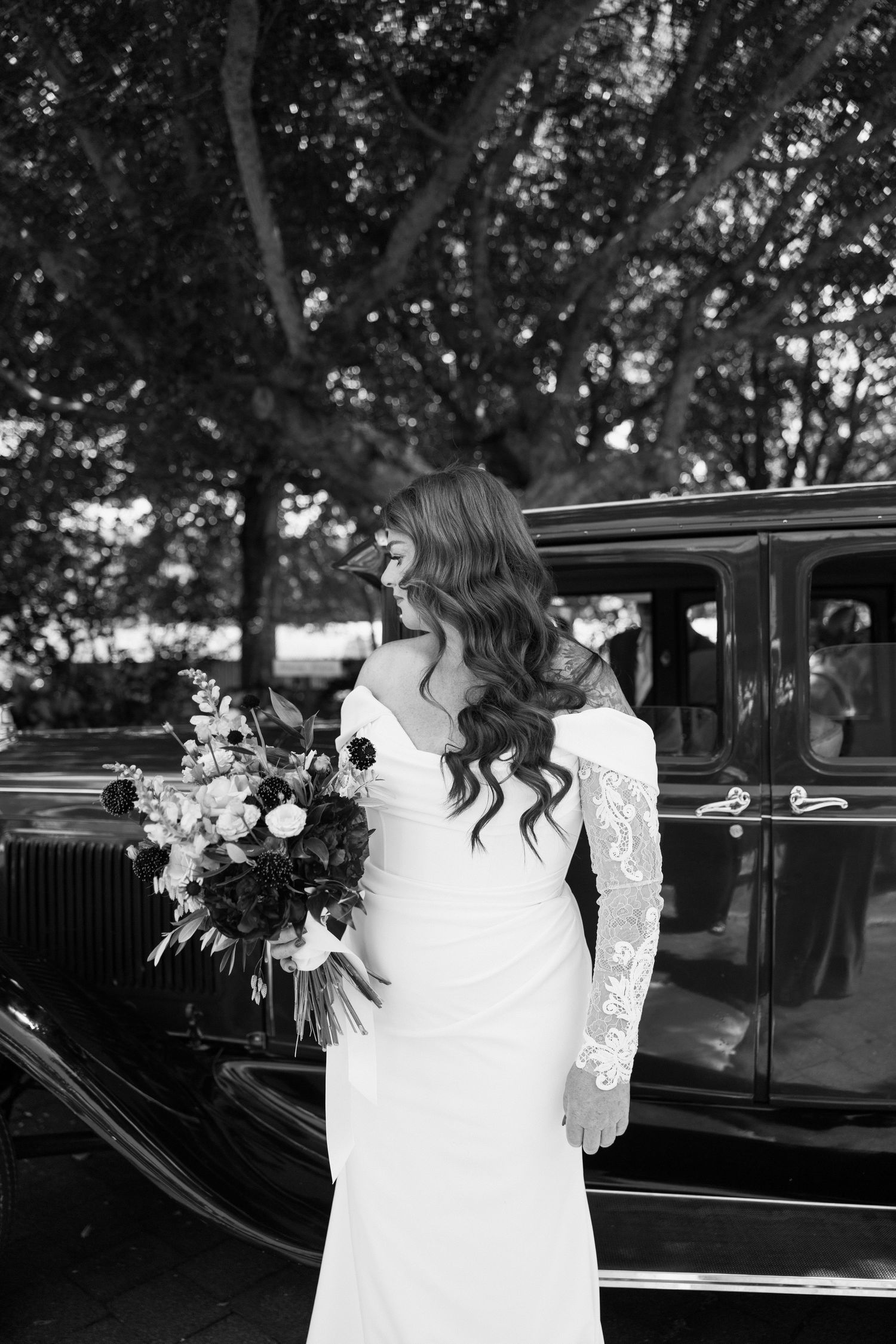 Black and white photo series showing someone in a white dress getting into a vintage car at a wedding.