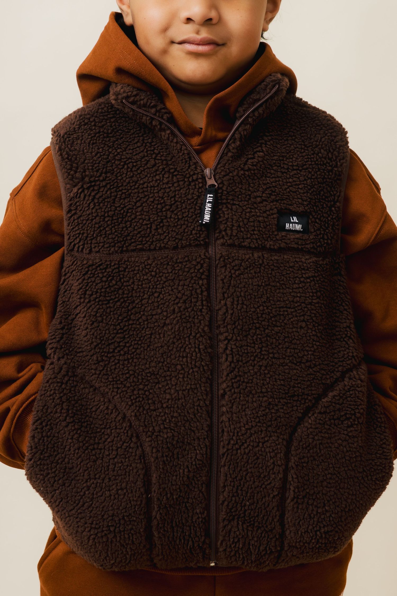 Close-up view of brown sherpa fleece vest with zip front closure shown from multiple angles.
