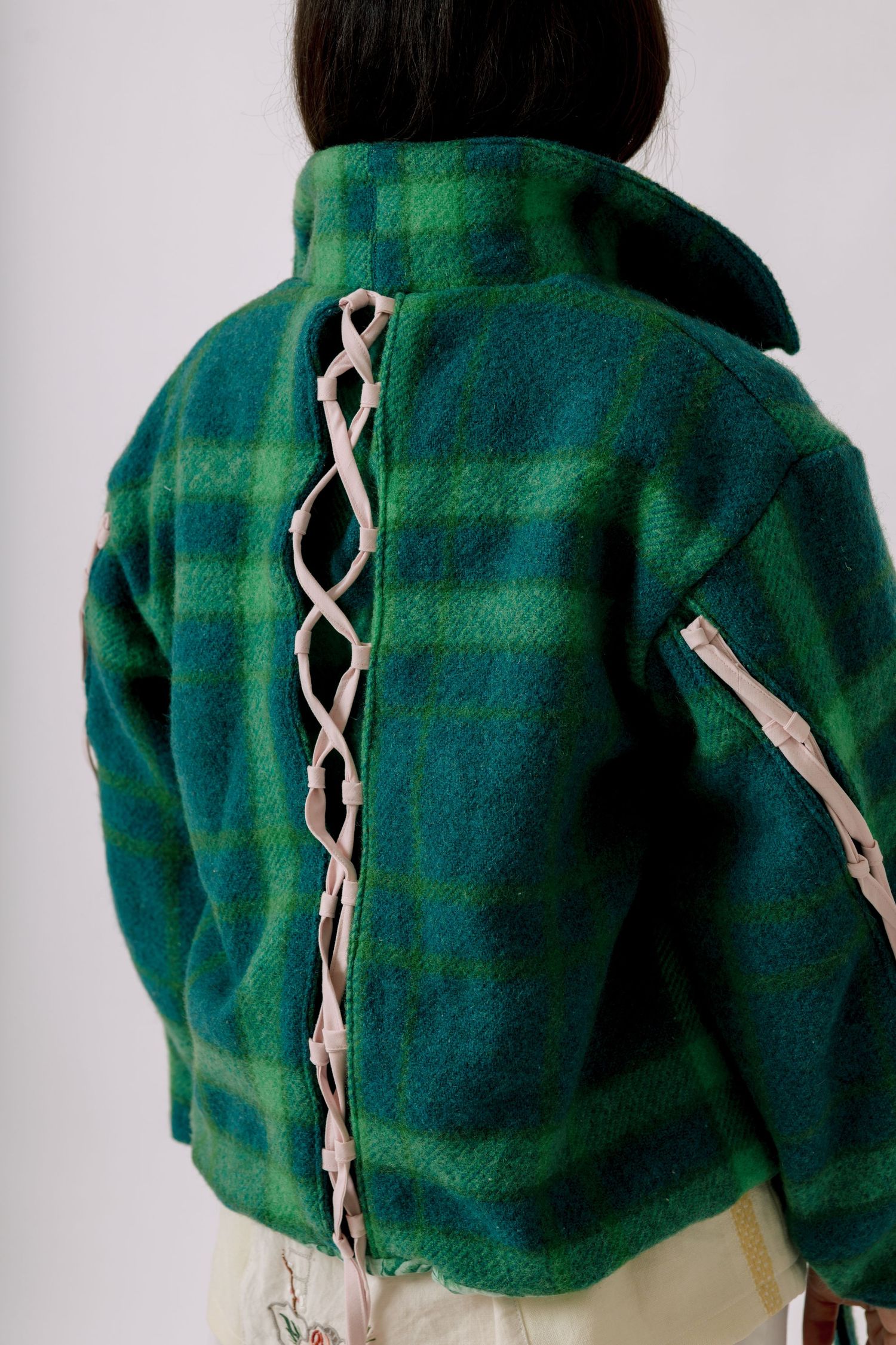 Green plaid fleece jacket with white lace-up corset detail along the back seam.