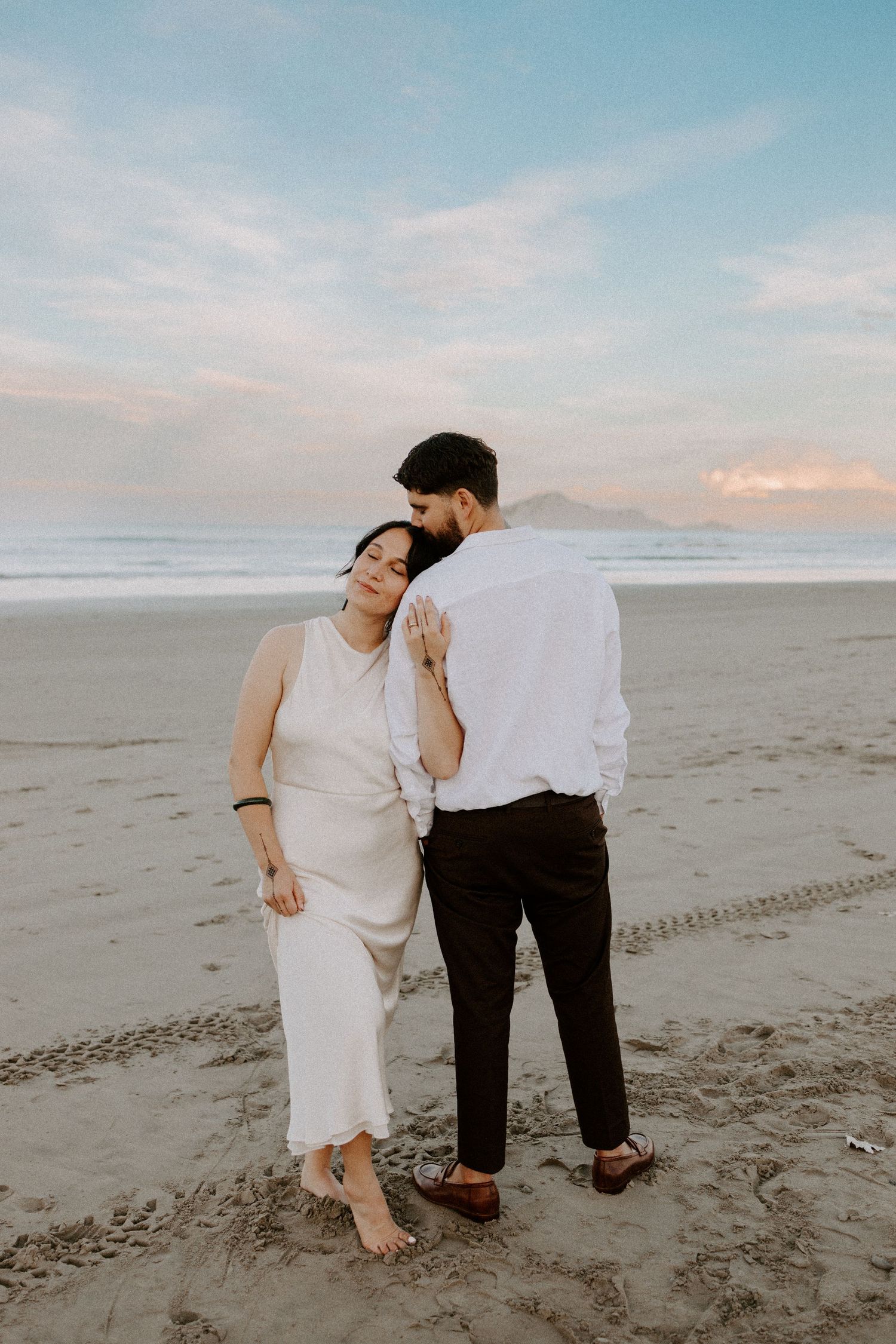 Romantic couple shares an intimate moment on a scenic beach at dusk.