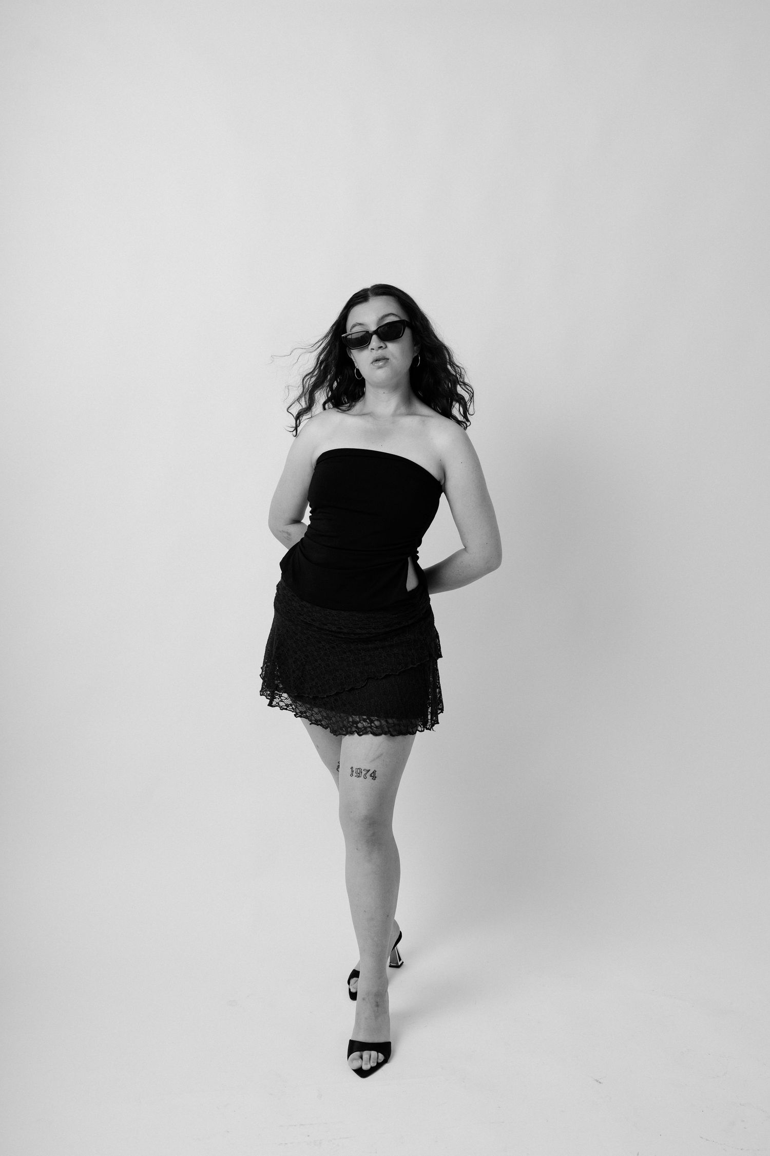 Black and white photo series showing a person in sunglasses and black dress posing in different dynamic positions.