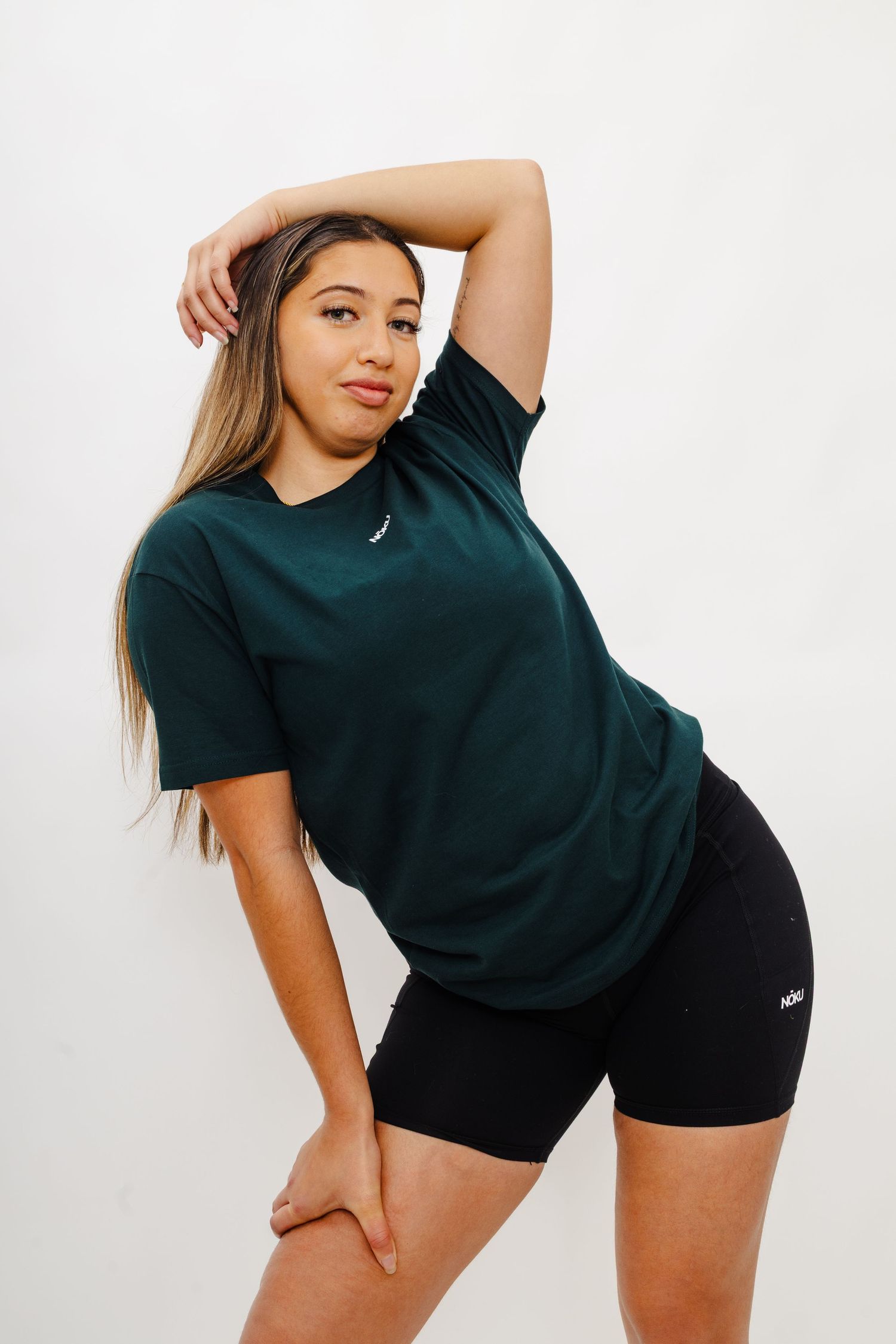 Athletic wear featuring a dark green t-shirt and black shorts in a stylish pose against white background.