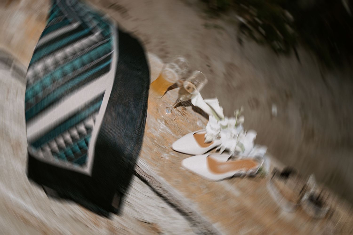 A pair of white bridal shoes on a textured floor with geometric patterns in the background.