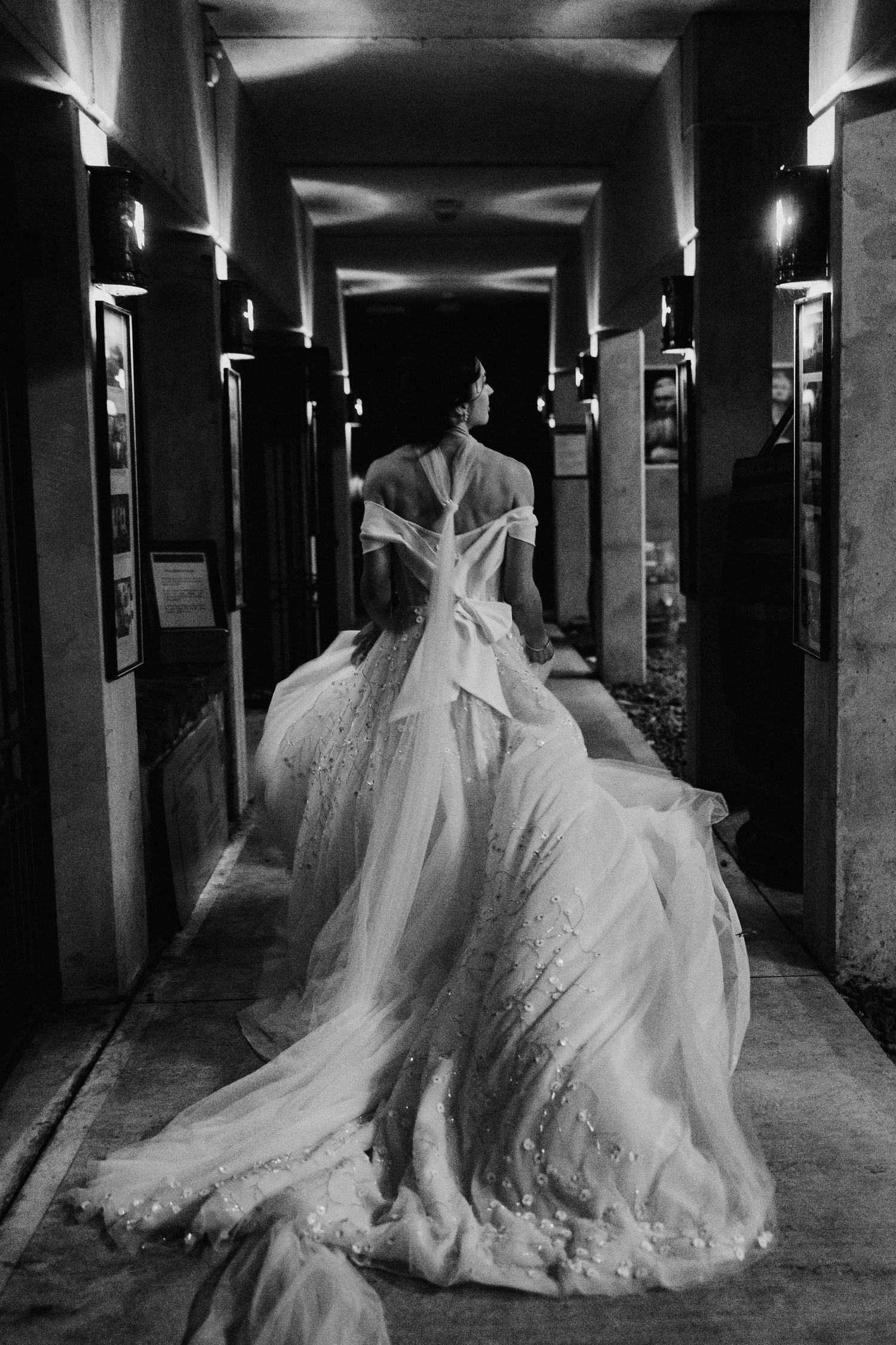 A dramatic series of black and white photos showing a billowing white wedding dress in a dark hallway.