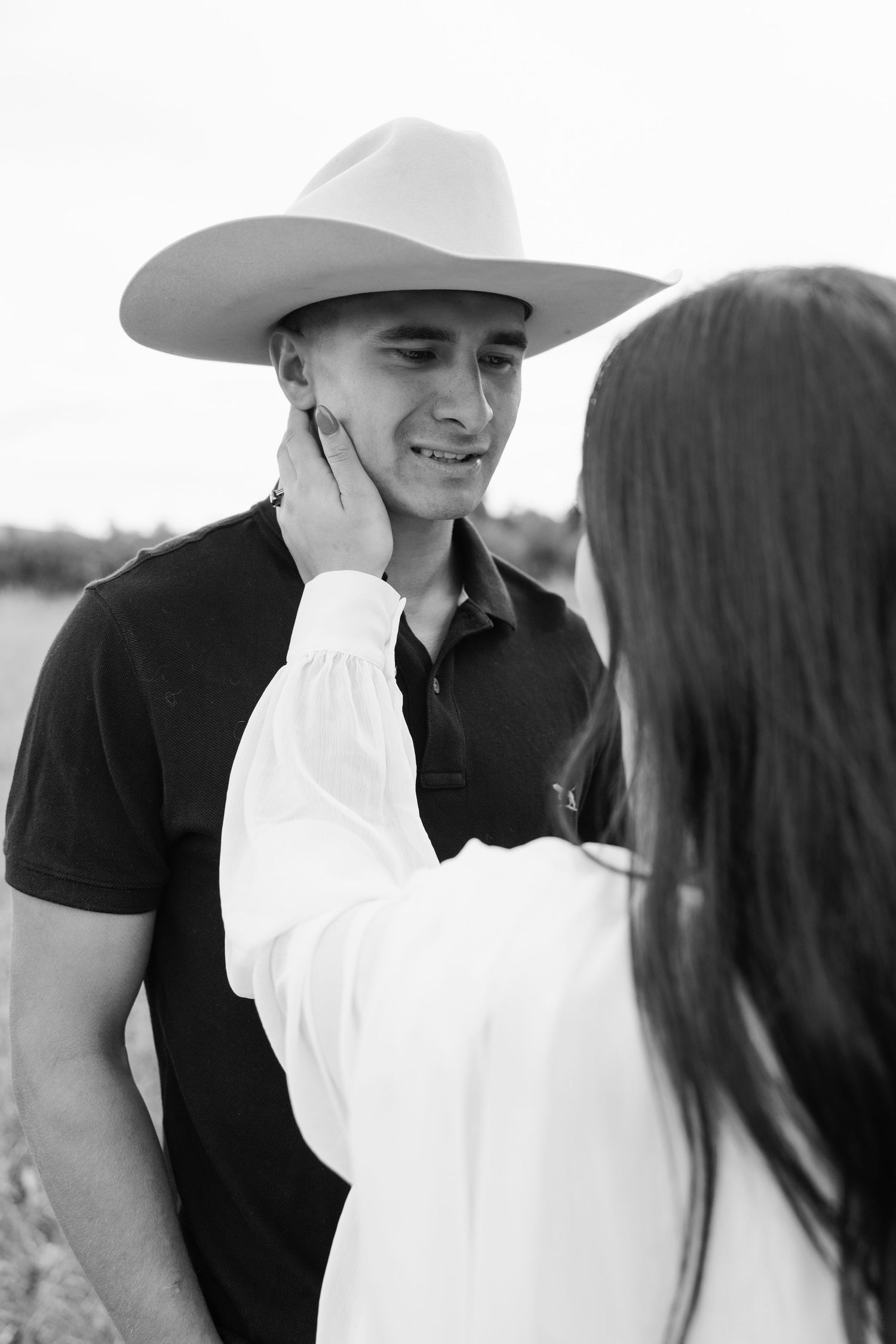 A romantic black and white photo series showing a couple in western attire sharing intimate moments outdoors.