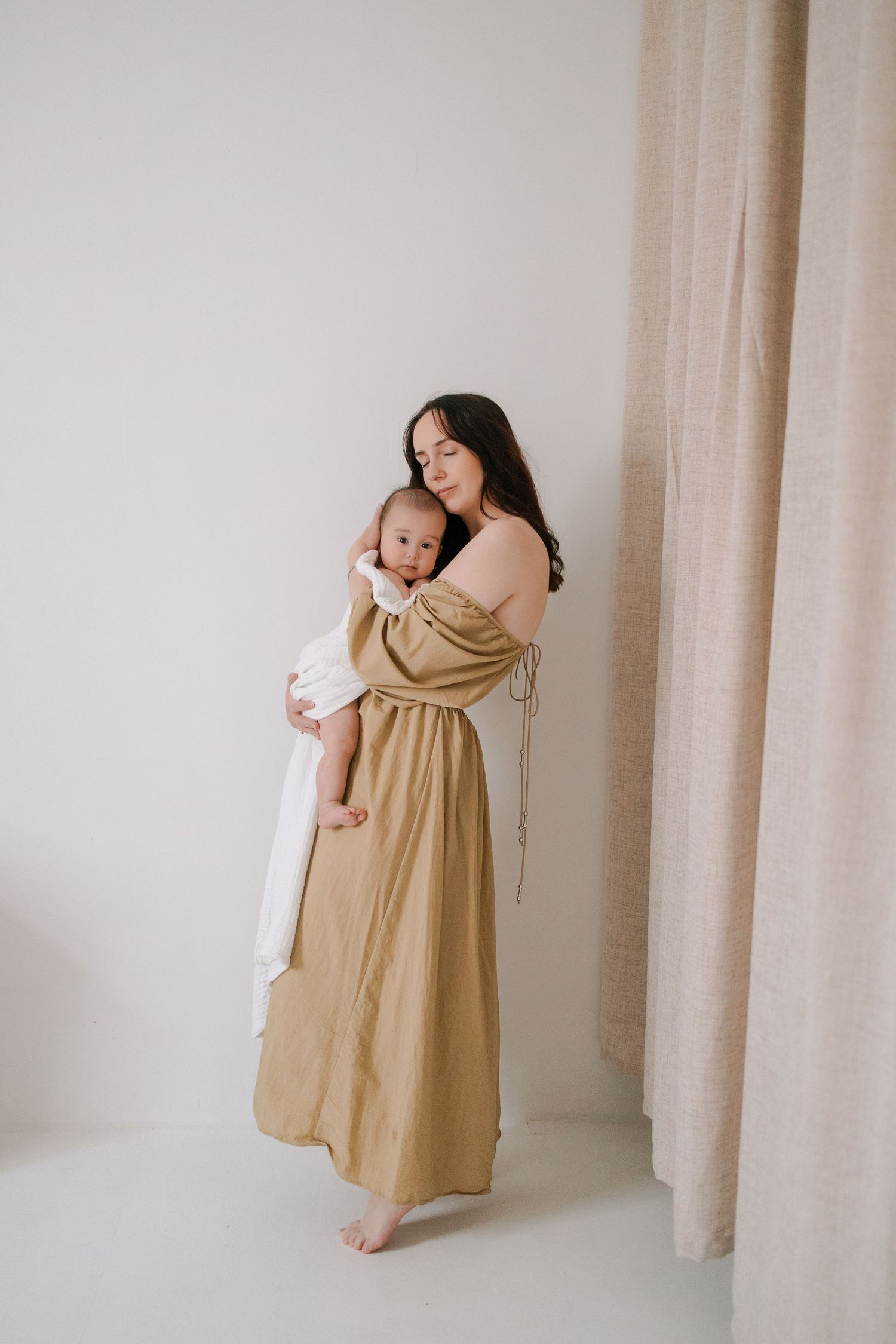 A series of minimalist photos showing tender moments between a parent and baby in beige tones against a light backdrop.