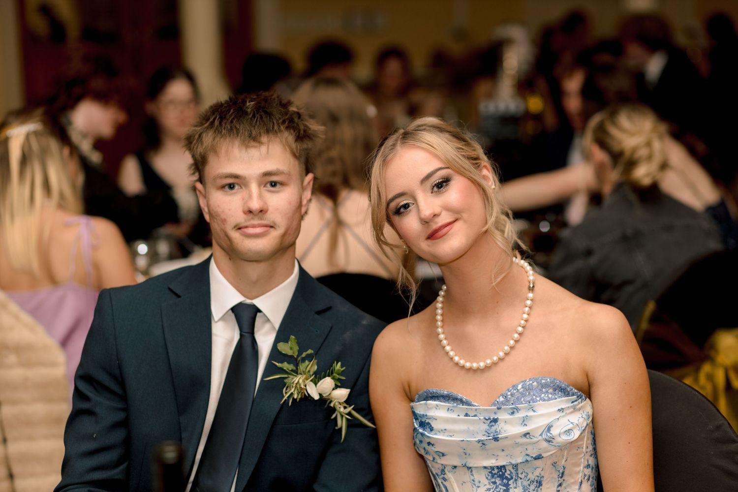Young couple dressed formally at a prom or gala event, girl wearing pearl necklace and blue strapless gown.