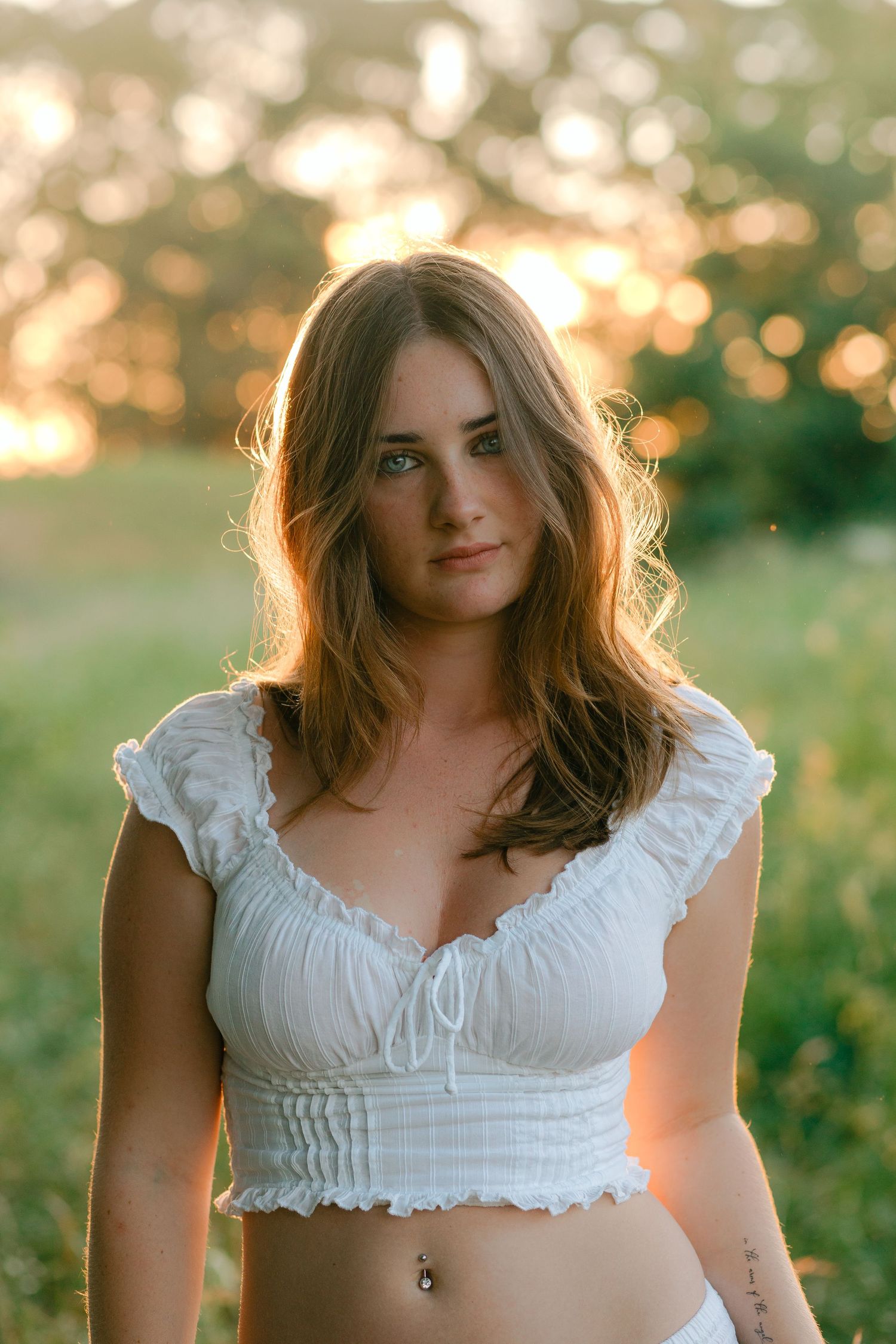A series of portraits in golden sunlight showing a white ruffled crop top against a natural outdoor backdrop.
