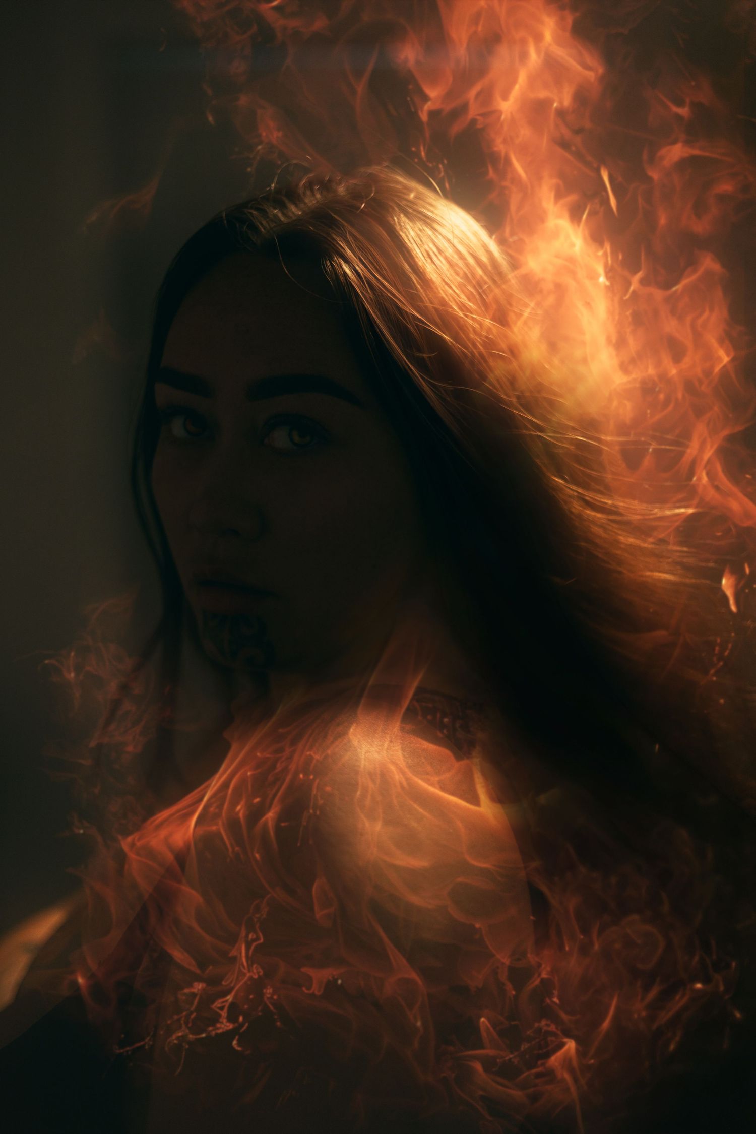 Artistic portrait surrounded by dramatic orange flames and fire effects in dark moody lighting.