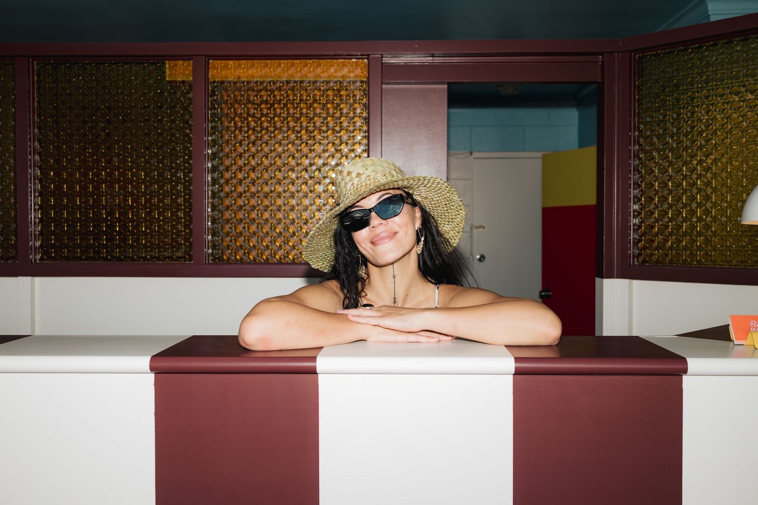 View of someone wearing a sun hat and sunglasses leaning on a diner counter.