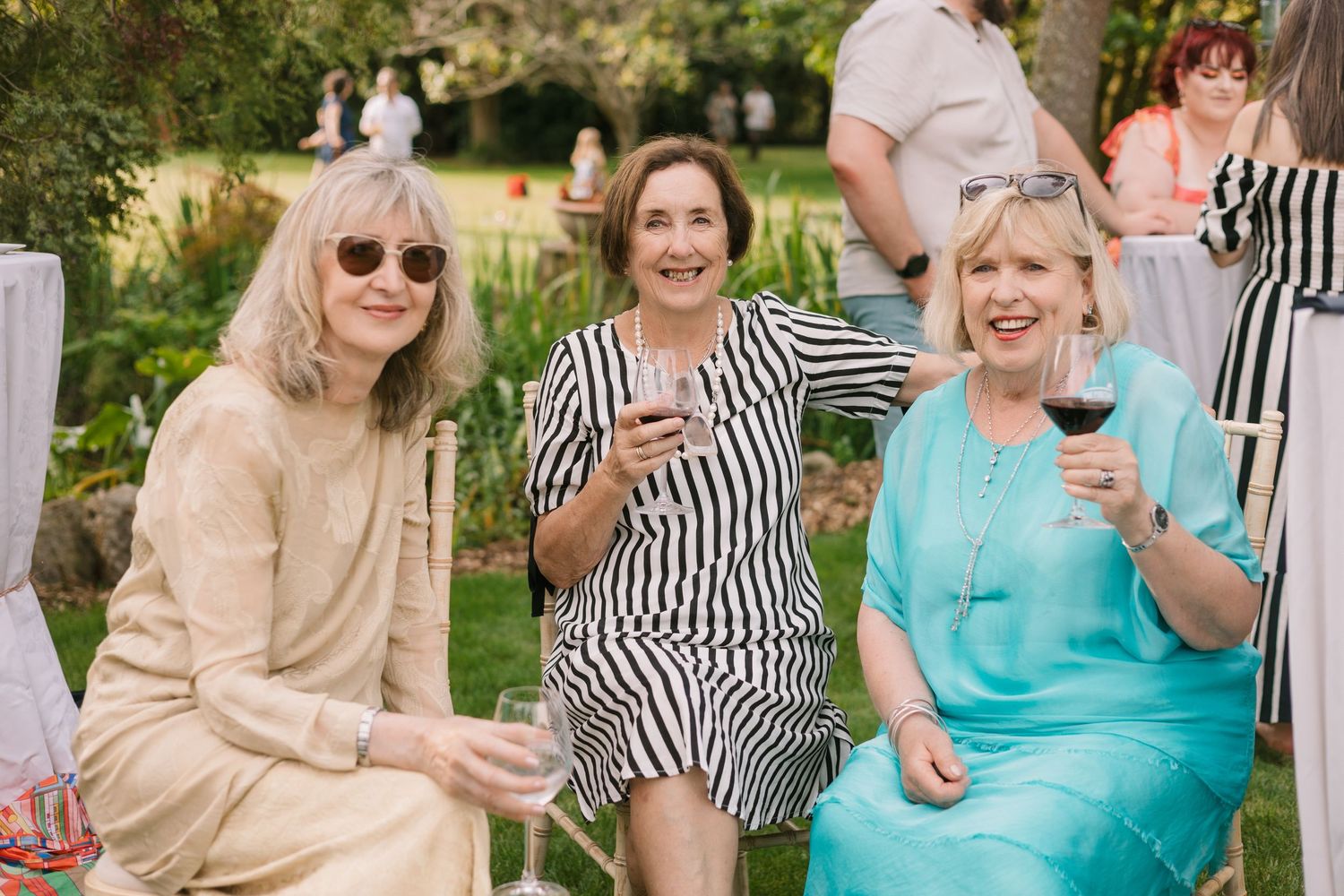 Wedding guests enjoying wine and conversation at outdoor garden reception.