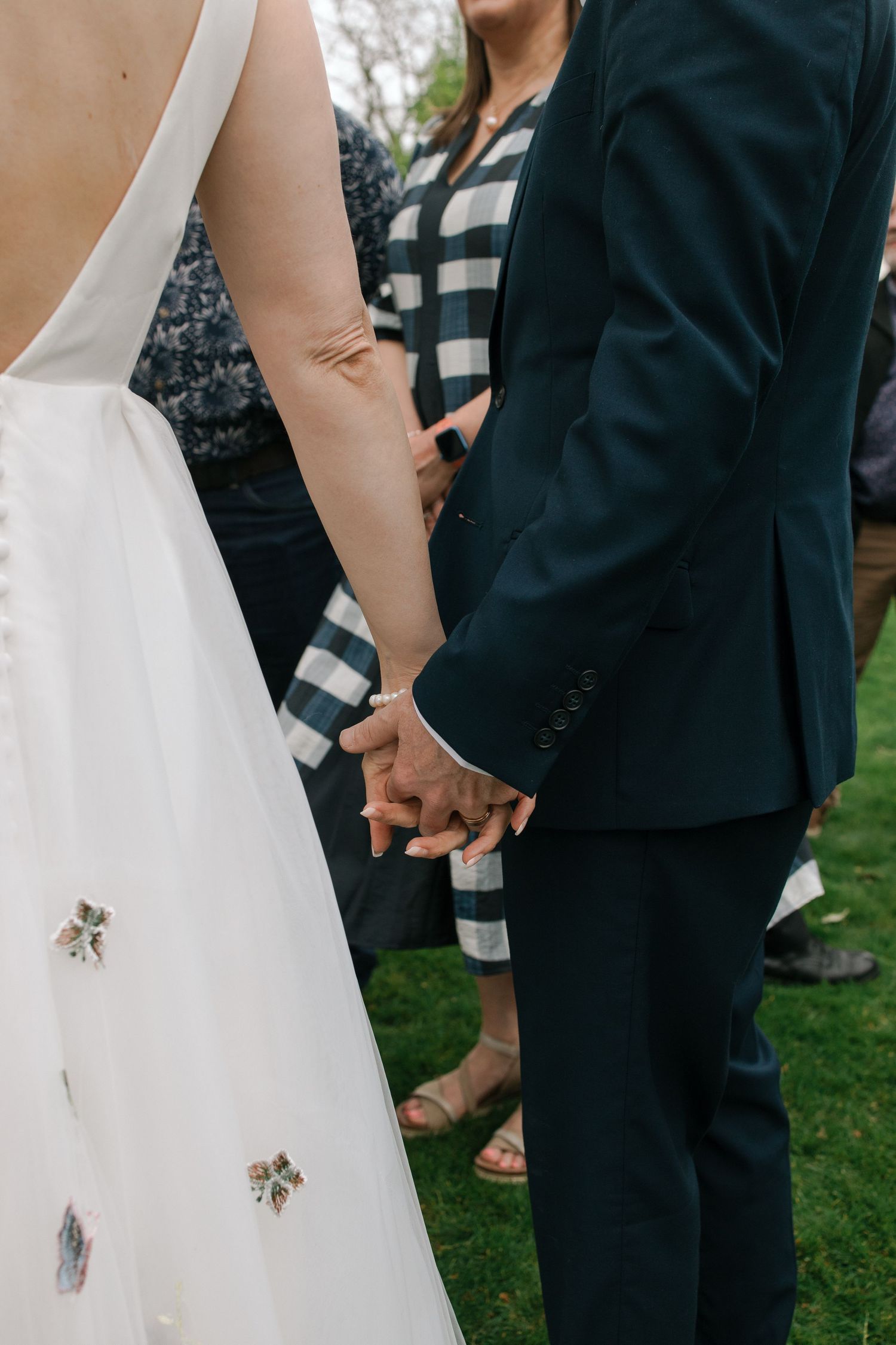 Close-up shots of a bride in white dress and groom in black tuxedo holding hands during their ceremony.