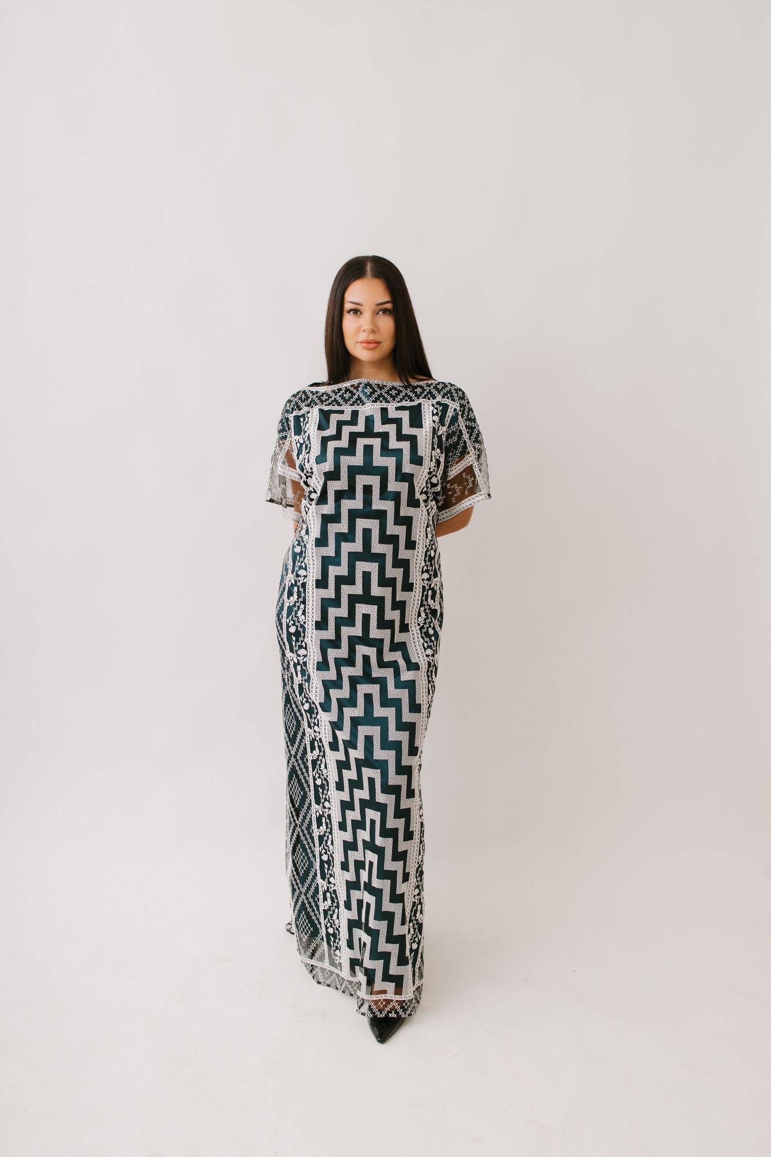 Model wearing a floor-length modern kaftan dress featuring a bold geometric zigzag pattern in black and white.