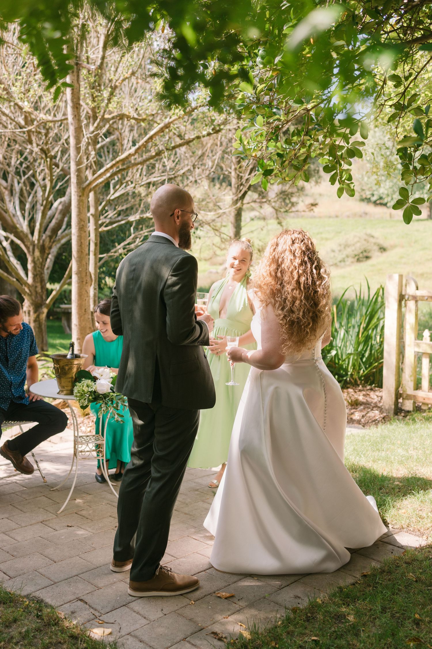 A couple dances together on a patio while guests in green dresses look on.