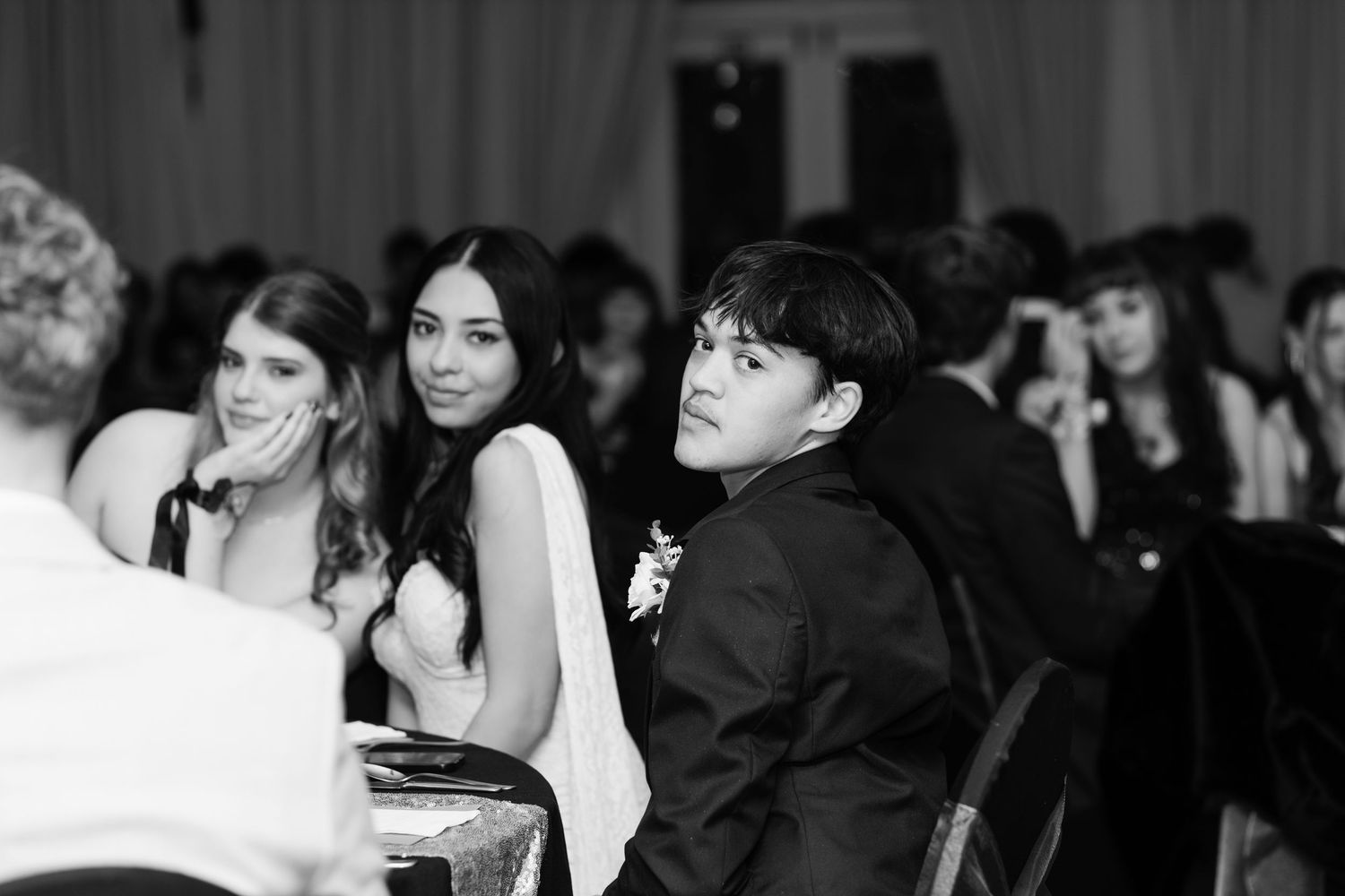 Black and white photo of elegantly dressed young couple at formal event, sitting together at banquet table.