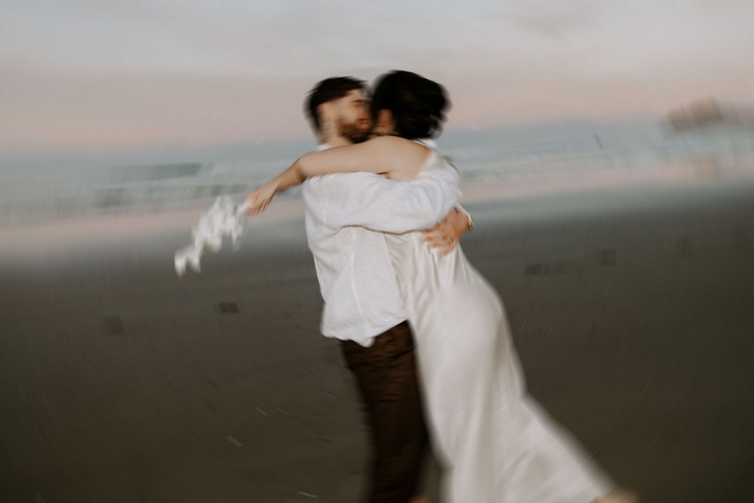 A romantic spinning embrace on a misty beach at sunset.