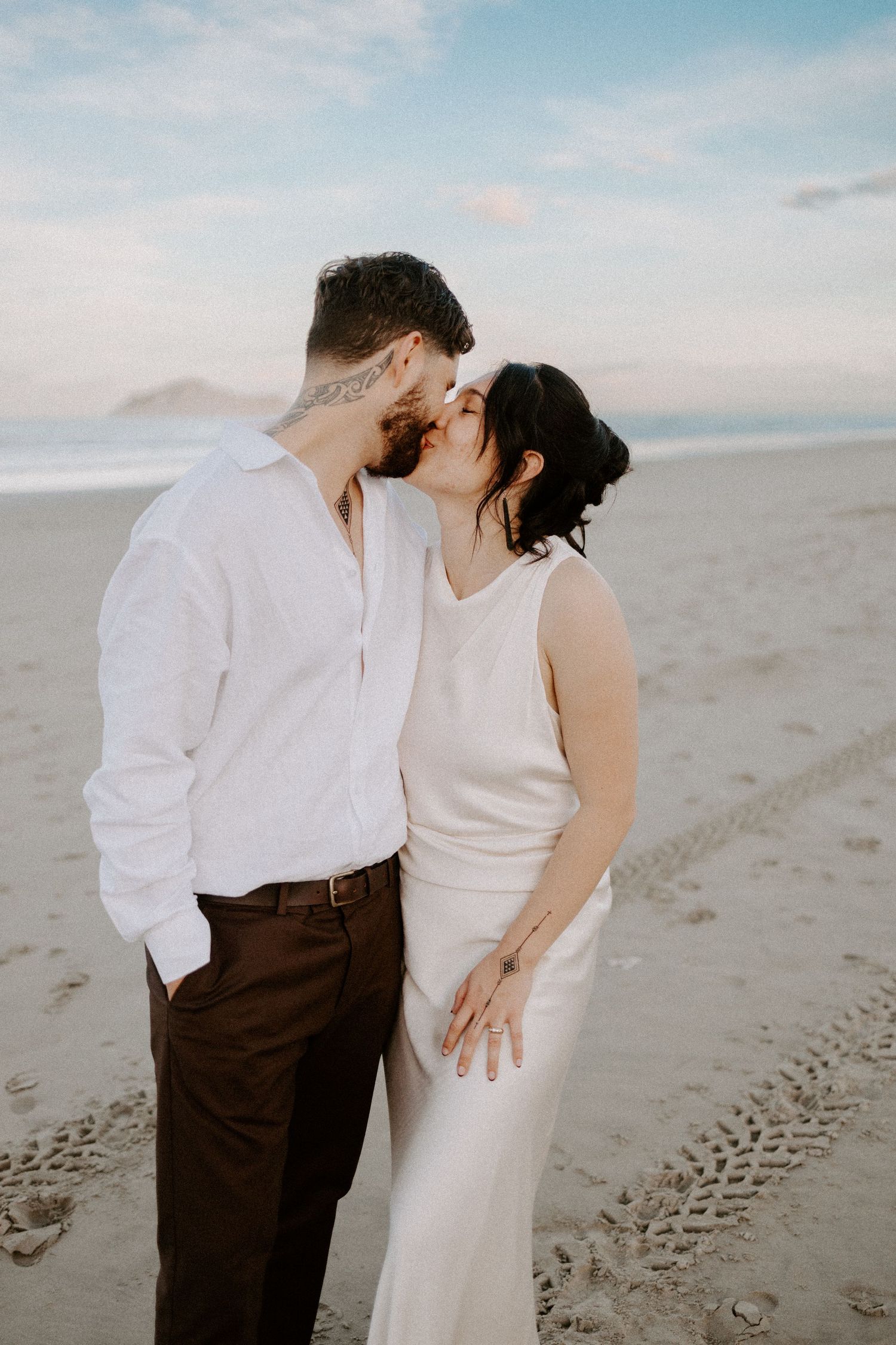 Romantic beach moment captured during sunset with soft pastel sky.